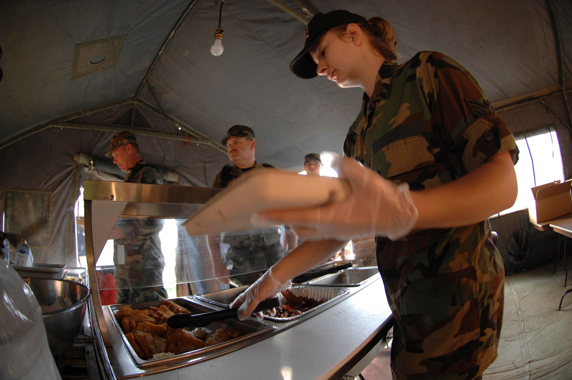 SHAW AIR FORCE BASE, S.C. -- Senior Airman Rachel Dunsmore, 20th Services Squadron food specialist, serves breakfast to members of the 20th Civil Engineer Squadron from a field kitchen during a field training exercise May 22. As part of the four-day FTX the 20th CES trained in self-aid buddy care, cardiopulmonary resuscitation, weapons safety, decontamination, security, land navigation, night operations and any job-specific training required. (U.S. Air Force photo by Airman First Class Kathrine McDowell)