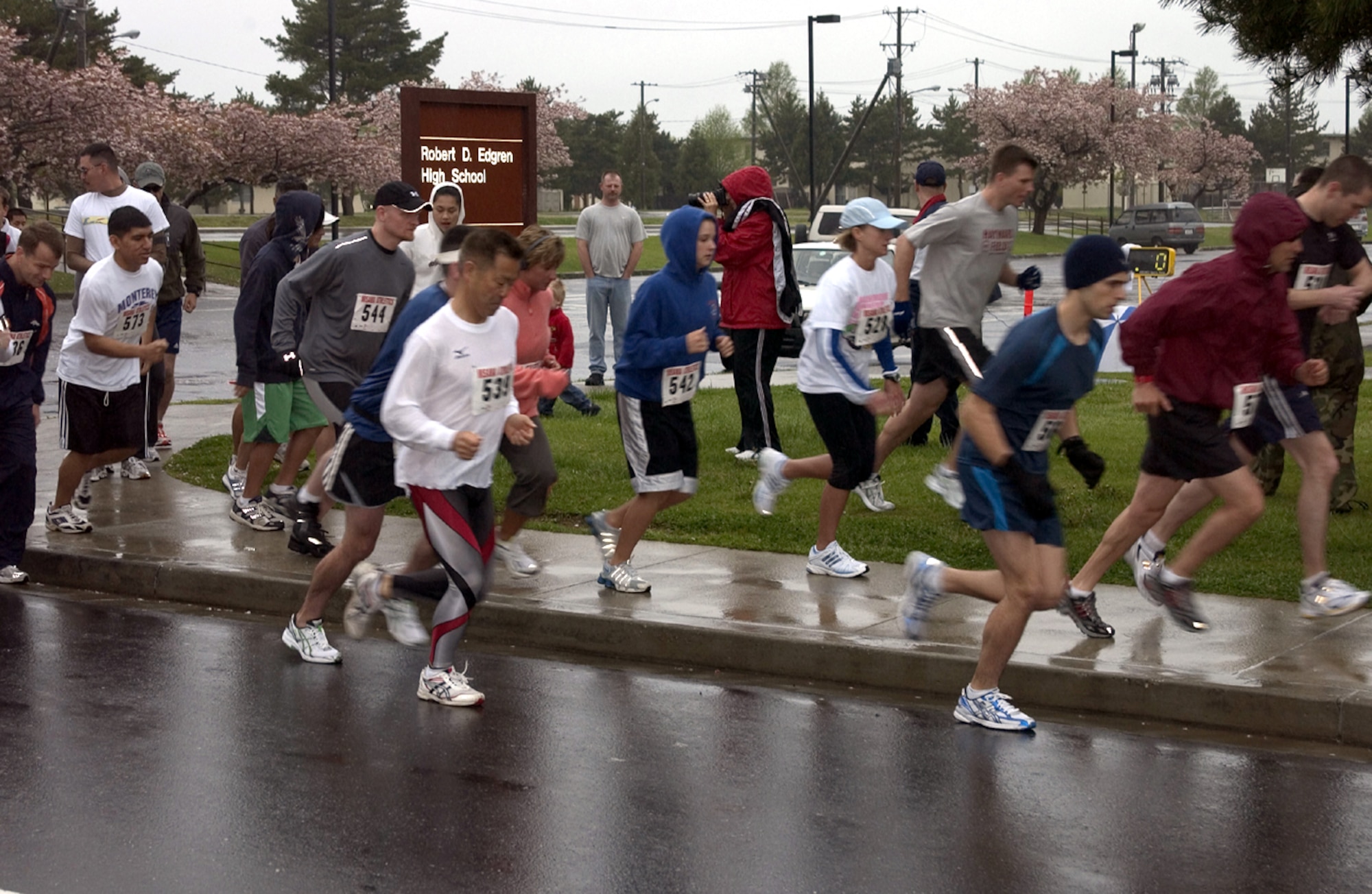 MISAWA AIR BASE JAPAN -- Runners begin their race in front of Edgren High School on here May 19. Runners that have numbers are registered to run to promote May Fitness Month. Forty-nine runners braved the blistery cold and rainy weather to run either a 5 or 10 kilometers. The run was organized by Potter Fitness Center with the help of the Asian-Pacific Heritage committee. The first place male runner was Kristoffer Chacon, 35th Services Squadron, with a time of 38:40. The first place female runner was Valerie Bell, 35th Operations Support Squadron, with a time of 46:53. Also placing in second and third were in both categories were Benjamin Chirlin, 35th Civil Engineer Squadron, with a time of 40:34 and Teiichi Horiuchi, 35th CES, with a time of 41:39 in the male category. In the female category, second place went to Lori Grant, family member, with a time of 49:41 and in third placeTeresa Giustino, family member, with a time 49:36. (U.S. Air Force photo by Airman 1st Class Eric Harris) 