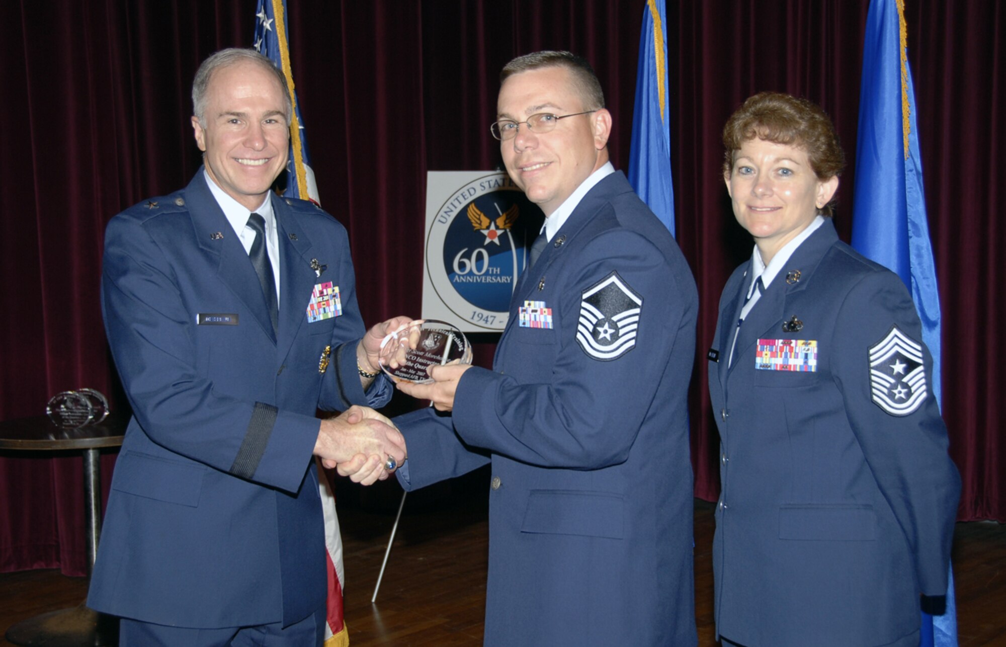 Master Sgt. Scott Morehouse accepts the Senior NCO Instructor of the Quarter award at the May 24 Quarterly Technical Training Awards in the base theater. The 383rd Training Squadron Optometry Apprentice Course supervistor chaired a detailed analysis group that created 11 realistic Air Expeditionary Force scenarios. He also led a six-person team to clean up a 2-mile section of road as part of the Adopt-a-Highway program. Also pictured is 82nd Training Wing Commander Brig. Gen. Richard Devereaux. (U.S. Air Force photo/Sandy Wassenmiller)