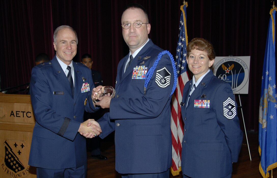 Master Sgt. Douglas Tigner of the 82nd Training Wing Training Operations office receives his award as the top Senior MTL at the May 24 Quarterly Tech Training Awards in the base theater. As the flight chief for wing military training, Sergeant Tigner coordination the transportation of 400 Airmen and eight military training leaders to a local hockey game, as well as completion of an Internet-base Iraqi familiarization course. Also pictured is 82nd Training Wing Commander Brig. Gen. Richard Devereaux. (U.S. Air Force photo/Sandy Wassenmiller)