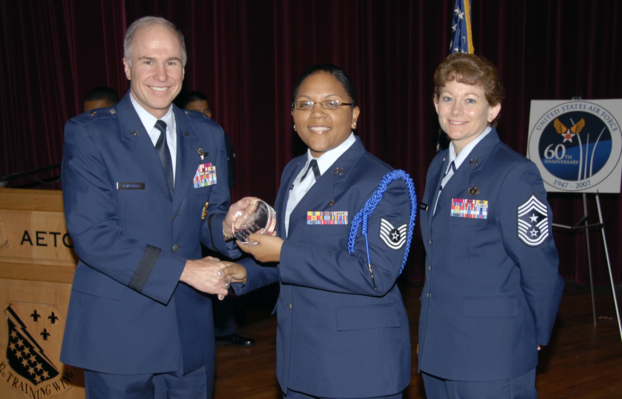 Tech. Sgt. Nicole Jones accepts the Junior MTL award at the Quarterly Tech Training Awards May 24 at the base theater. Sergeant Jones oversaw a $3,000 dorm restoration project for the 363rd Training Squadron and led her flight's Airmen-in-Training recognition program. She ensured the safe return home of six Sheppard personnel through the Airmen Against Drunk Driving program. Also pictured is 82nd Training Wing Commander Brig. Gen. Richard Devereaux. (U.S. Air Force photo/Sandy Wassenmiller)