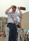 Lackland Ambassador Capt. Brent Dishman, riding the joint military float in the Battle of Flowers Parade on April 27, dons a string of Fiesta beads handed to him by aparade spectator at Broadway and Third Street. Fiesta is an annual 10-day event with more than 100 scheduled events designed to honor the heroes of the Alamoand the Battle of San Jacinto. Lackland AFB, Texas, is represented in numerousevents during the celebration, including the opening ceremonies, the Texas Cavaliers River Parade, the Battle of Flowers Parade, the Fiesta Flambeau night parade, Fiesta in Blue, the Air Force at the Alamo and the Fiesta Military Paradeon base. (USAF photo by Alan Boedeker)                 
