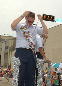 Lackland Ambassador Capt. Brent Dishman, riding the joint military float in the Battle of Flowers Parade on April 27, dons a string of Fiesta beads handed to him by a
parade spectator at Broadway and Third Street. Fiesta is an annual 10-day event with more than 100 scheduled events designed to honor the heroes of the Alamo
and the Battle of San Jacinto. Lackland AFB, Texas, is represented in numerous
events during the celebration, including the opening ceremonies, the Texas Cavaliers River Parade, the Battle of Flowers Parade, the Fiesta Flambeau night parade, Fiesta in Blue, the Air Force at the Alamo and the Fiesta Military Parade
on base. (USAF photo by Alan Boedeker)                 