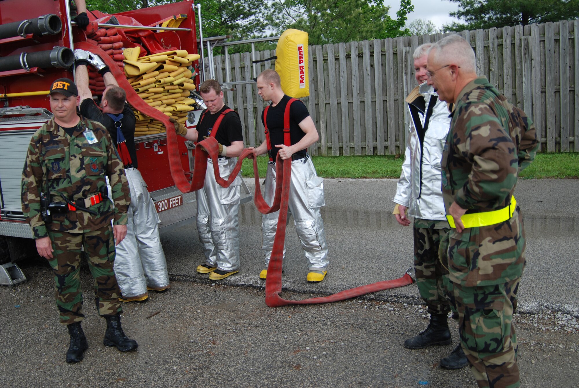 932nd Airlift Wing firefighting at its best in Illinois.  Firefighters roll hoses back on to their truck while Chief Master Sgt. Ralph Browning, Command Chief Master Sgt. Merle Lyman and Col. James Patterson share "fresh air" after their time in the firefighting suits for a four day exercise.