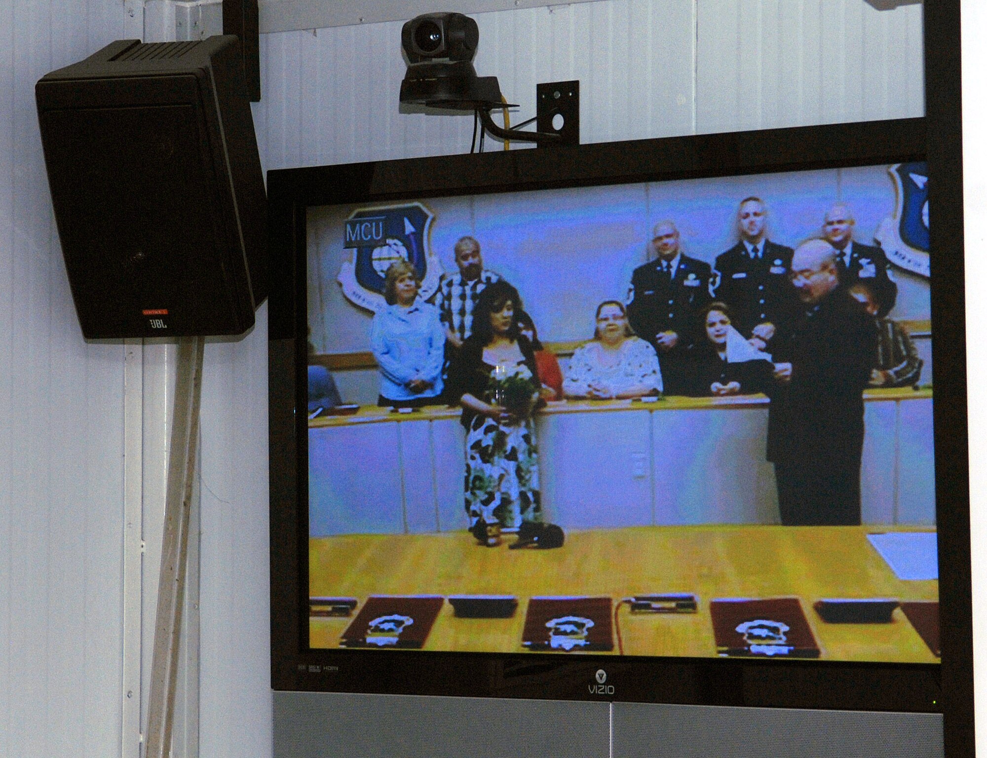 Senior Airman Carlos Moreno's fiancee, Carolina, listens as the priest recites the vows for her to repeat during a video teleconferece wedding from Vandenberg Air Force Base, Calif., to Bagram Airfield, Afghanistan May 26. Airman Moreno is assigned to the 455th Expeditionary Security Forces Squadron at Bagram and several members of his squadron were present to witness and show their support. Airman Moreno is deployed from the 30th Security Forces Squadron, Vandenberg. (photo by Staff Sgt. Craig Seals)