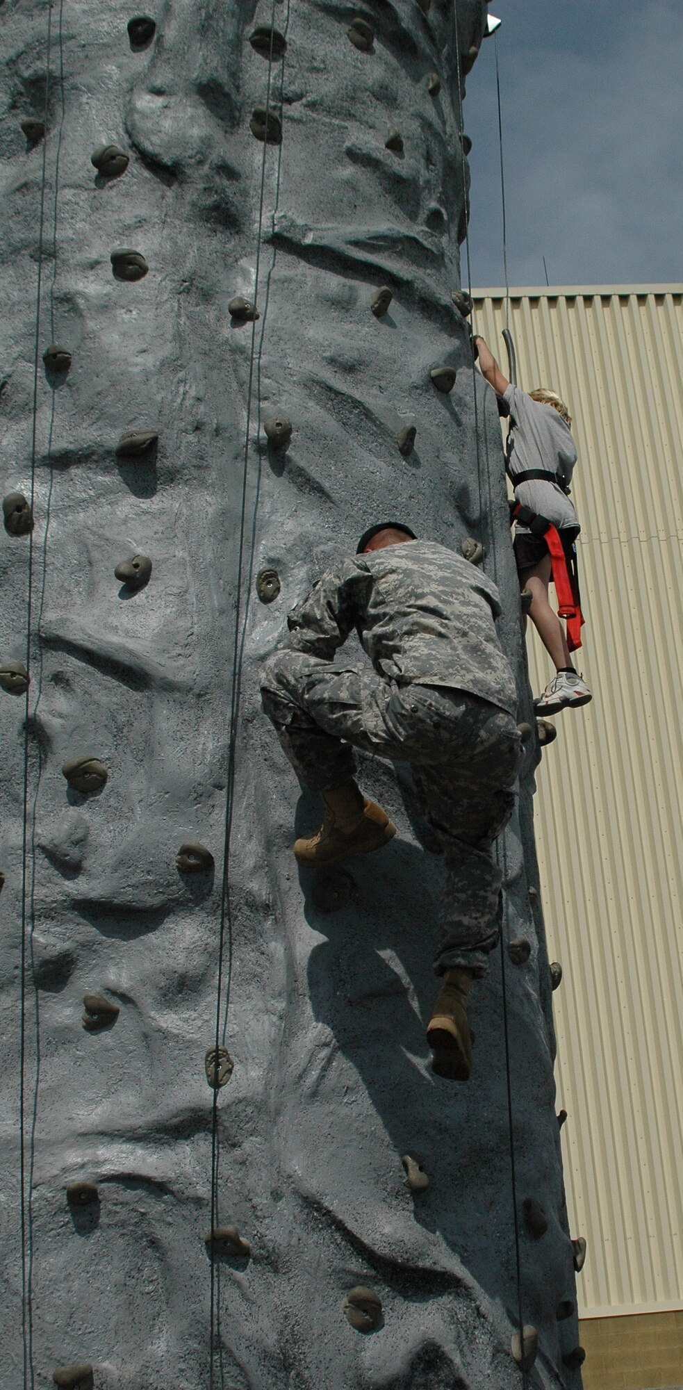 Army Spec. Jeb Reeves climbs the rock wall to assist Little Warrior Austin, 11, to the top during Malmstrom's open house and air show May 20. (U.S. Air Force photo by Airman 1st Class Emerald Ralston)