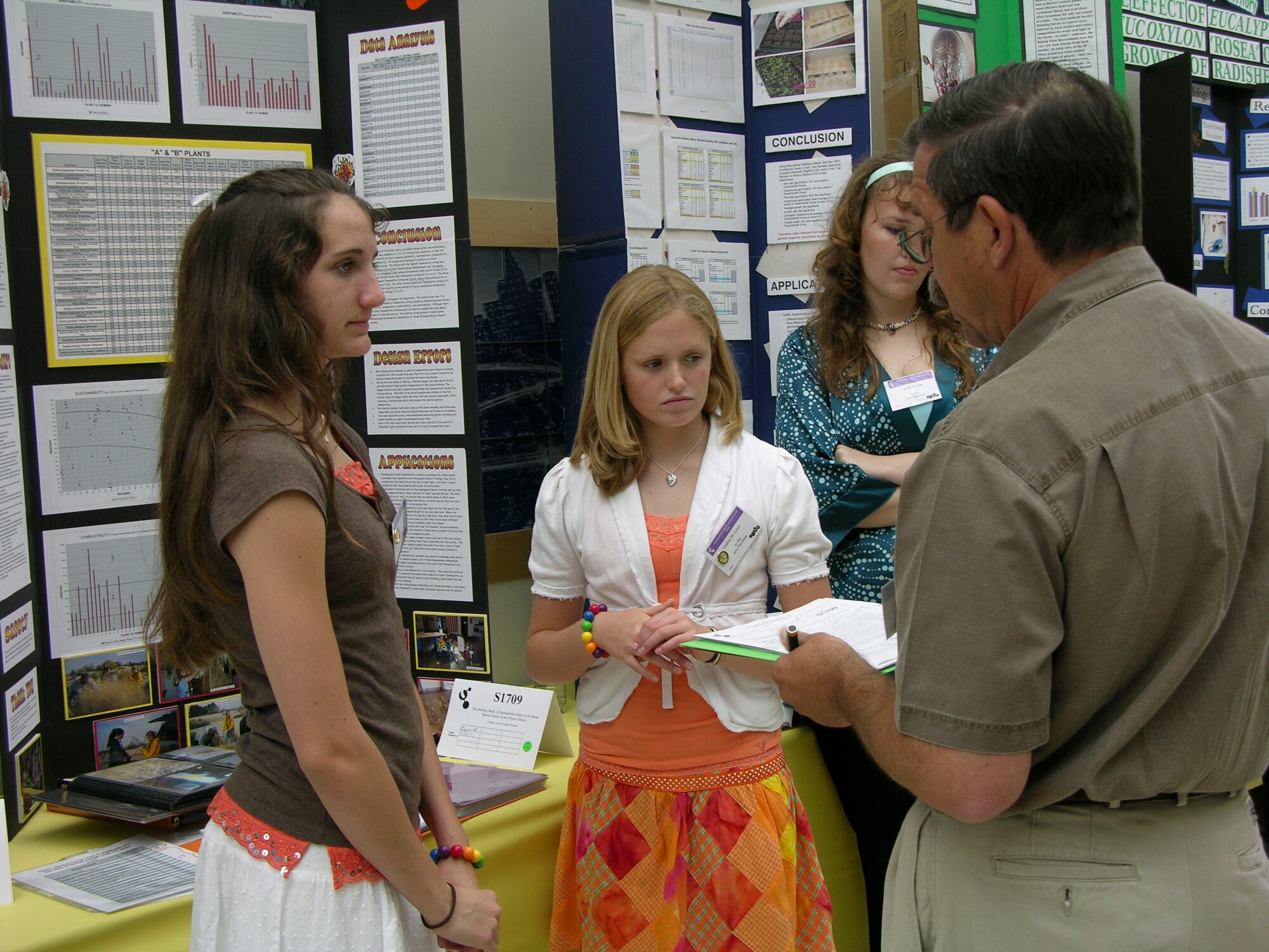 LOS ANGELES -- Kaitlyn Wright (left) and Lindsey Lewis (center), Desert High School seniors, explain their project to one of the judges during the California State Science Fair at the California Science Center in Los Angeles on May 22. Ms. Lewis and Ms. Wright received first place for their plant biology project. Kehly Kirk, another DHS student, placed third, also for plant biology. Robert Thurman and Keith Hines, both DHS seniors, also received a special award for doing a low-cost and hands-on project. (Photo by Dawn Waldman)