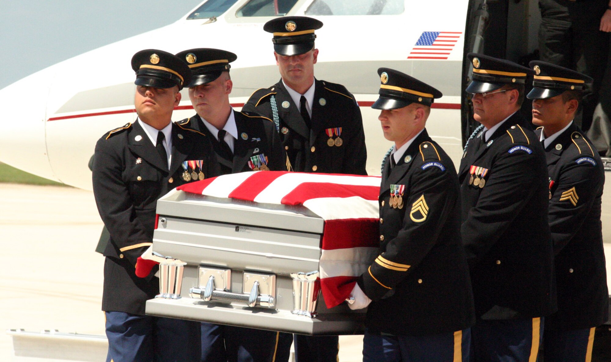 LAUGHLIN AIR FORCE BASE, Texas -- Honor Guard members from Fort Sam Houston carries the American Flag draped casket of U.S. Army Pvt. Oscar Sauceda Jr., 21. With a group of his family close by, a small charter plane carrying his body touched down at Laughlin May 29, to bring him home town of Del Rio, Texas.(U.S. Air Force photo by Airman Sara Csurilla)