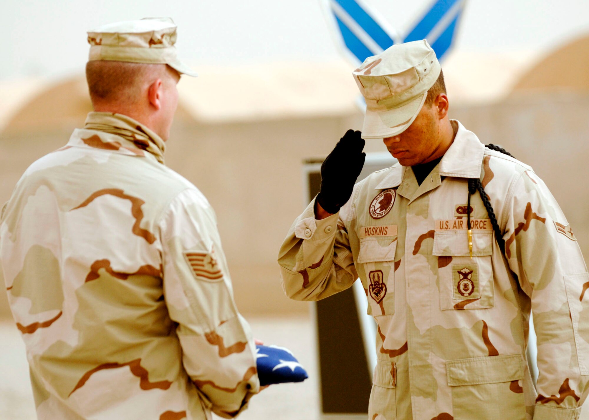 Airman 1st Class Derik Hoskins salutes the flag after presenting it to Tech. Sgt. Clinton Taylor during a fallen Airmen ceremony May 28 in remembrance of Staff Sgt. John Self at Ali Air Base, Iraq. The Airmen, both members of the 407th Expeditionary Security Forces Squadron, were participating in the ceremony honoring the life of Sergeant Self, a security forces member assigned to the 732nd Expeditionary Security Forces Squadron at Camp Bucca, Iraq, who was killed May 14 by an improvised explosive device while on patrol. (U.S. Air Force photo/Master Sgt. Robert W. Valenca)