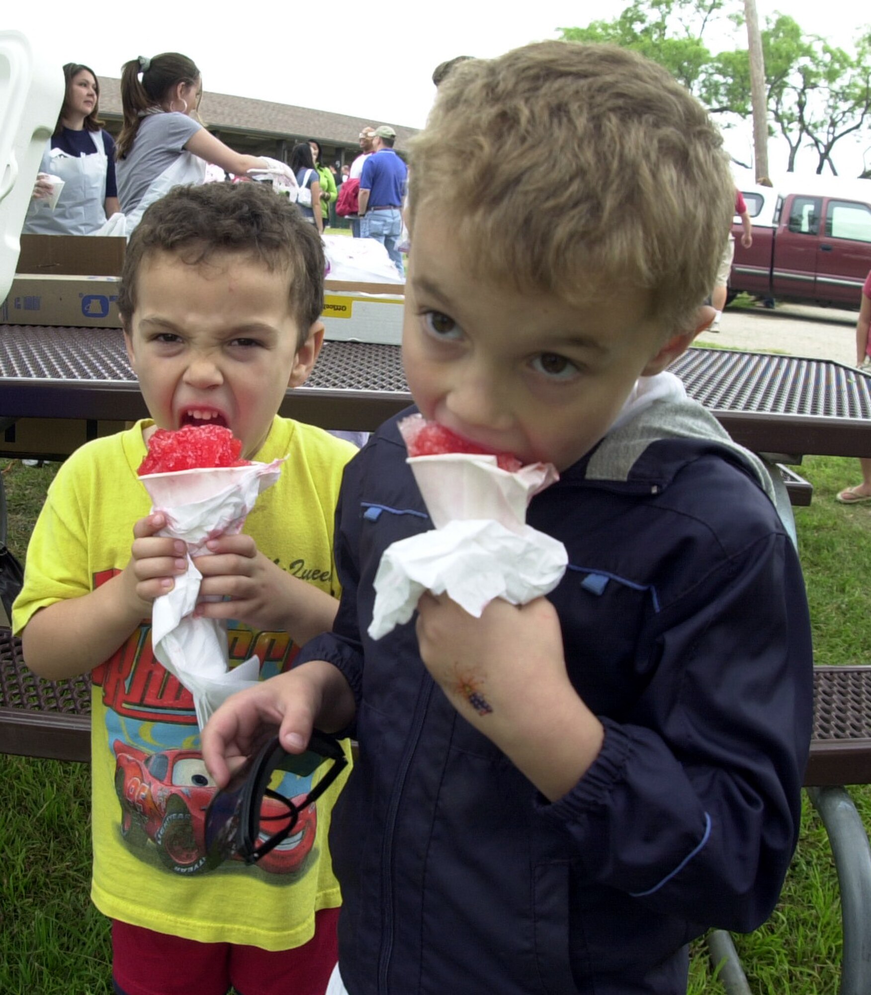 Four-year-old Matthew Baker and his six-year-old brother Michael take big bites of the free strawberry snow cones at the Goodfellow Appreciation Day picnic May 19. (U.S. Air Force photo by Airman 1st Class Luis Loza Gutierrez)