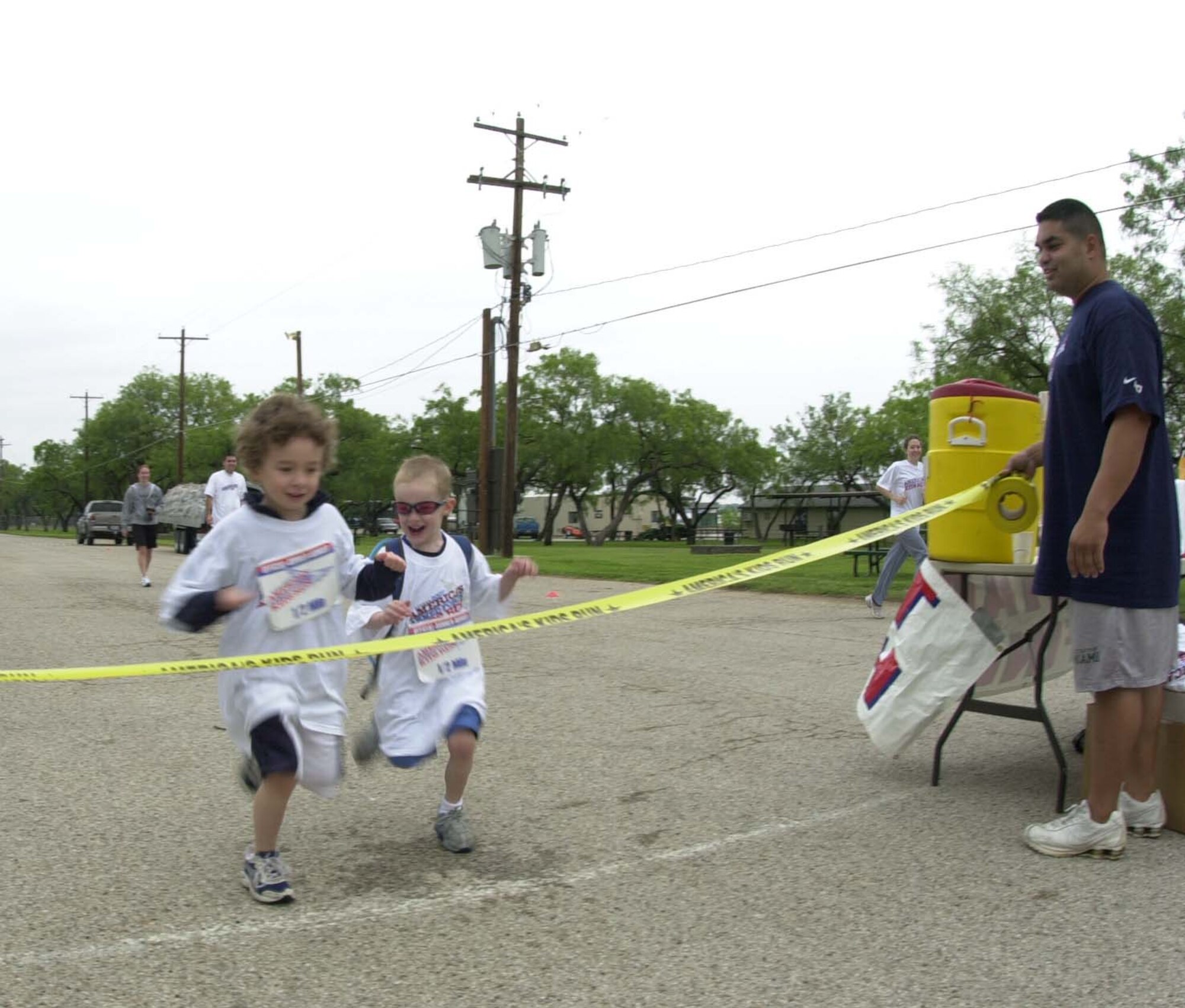 Omar Matos, Goodfellow Youth Programs sports and fitness director, watches as two young athletes dash to the finish line during the 2007 America’s Armed Forces Kids Run May 19 at the Goodfellow Recreational Camp at Lake Nasworthy. (U.S. Air Force photo by Airman 1st Class Luis Loza Gutierrez)