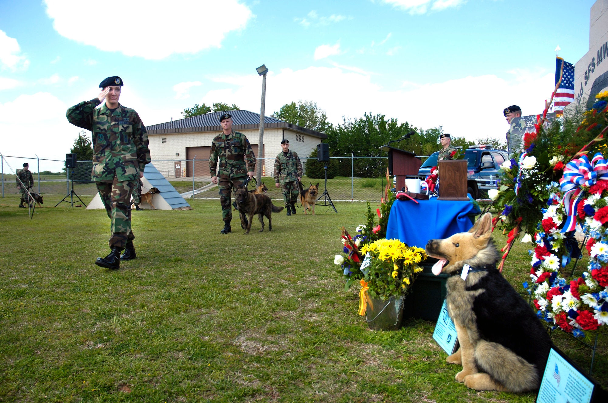 Staff Sgt. Alissa Jones salutes as she passes the memorial display for military working dog Marco during a recent memorial ceremony at Tinker Air Force Base, Okla.  Sergeant Jones and Marco were deployed to Iraq when the dog was electrocuted Jan. 19 while patrolling for bomb-making materials and weapons in Baghdad.  Following Sergeant Jones are: Staff Sgt. Brent Reimers with MWD Bratling; and Staff Sgt. Arthur Dennis with MWD Jambo. (U.S. Air Force photo by Dave Faytinger)