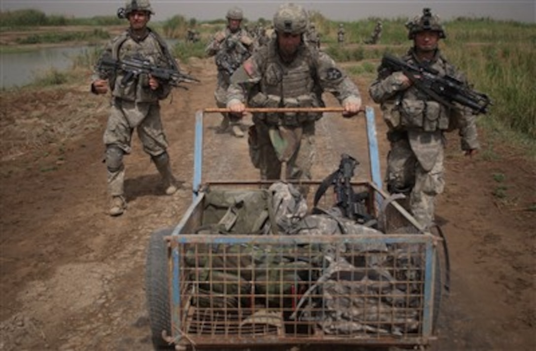 U.S. Army Sgt. Timothy French pushes a cart to pick up a weapons cache discovered during a search for missing soldiers in Iskanderiyah, Iraq, on May 25, 2007. French is from Bravo Company, 1st Battalion, 23rd Infantry Regiment, 3rd Stryker Brigade Combat Team, 2nd Infantry Division deployed from Fort Lewis, Wash.  