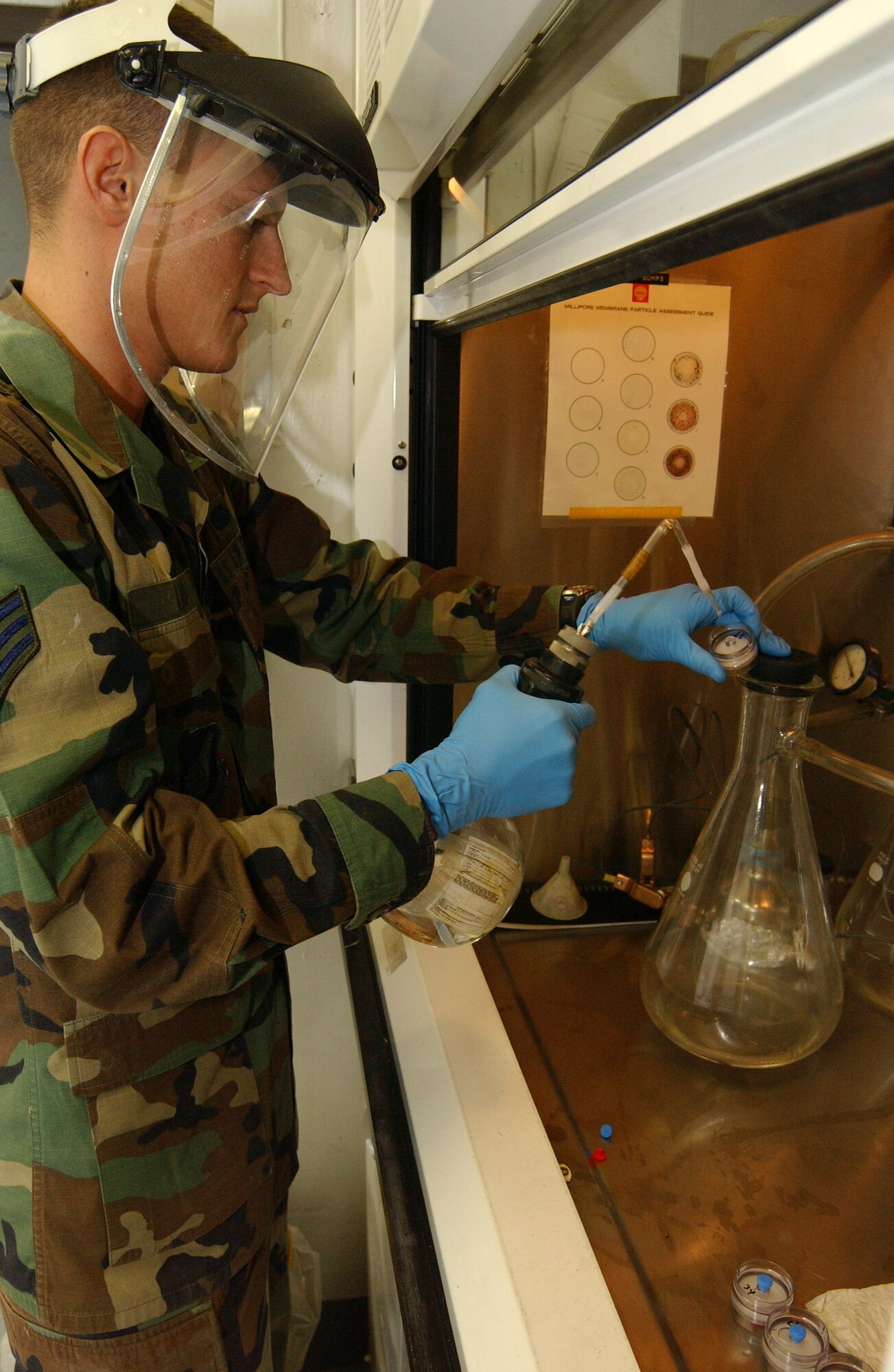 EIELSON AIR FORCE BASE, Alaska -- Senior Airman John Lind, 354th Logistics Readiness Squadron fuels management flight, performs a color in particulate assessment May 24 in the fuels management laboratory.  Airman Lind is rinsing a single weight minitor (essentially, a fuel filter) with ether, a highly flammable solvent that removes fuel from the filter, to better see the fuel particulates of the solid contamination. This process uses a vacuum inside a fume hood to ensure safety from these highly flammable and toxic substances.  (U.S. Air Force photo by Senior Airman Rachel Walters) 
