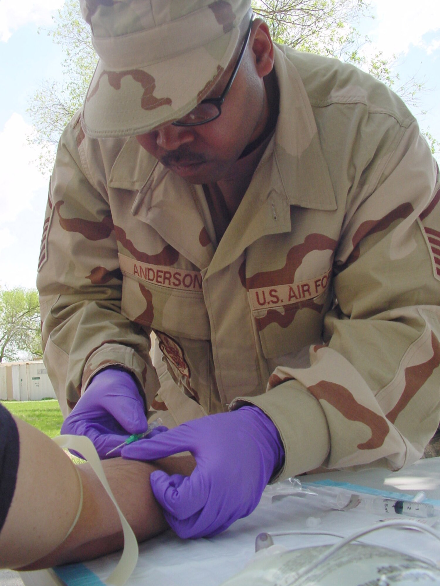 Sergeant Anderson searches for a patient’s vein before inserting a catheter tube into the person’s arm, so he can draw blood during transition team training at Fort Riley, Kan. Sergeant Anderson is attending the 60-day, pre-deployment training from McConnell Air Force Base. (Photo by Army Master Sgt. Jack Lee). 