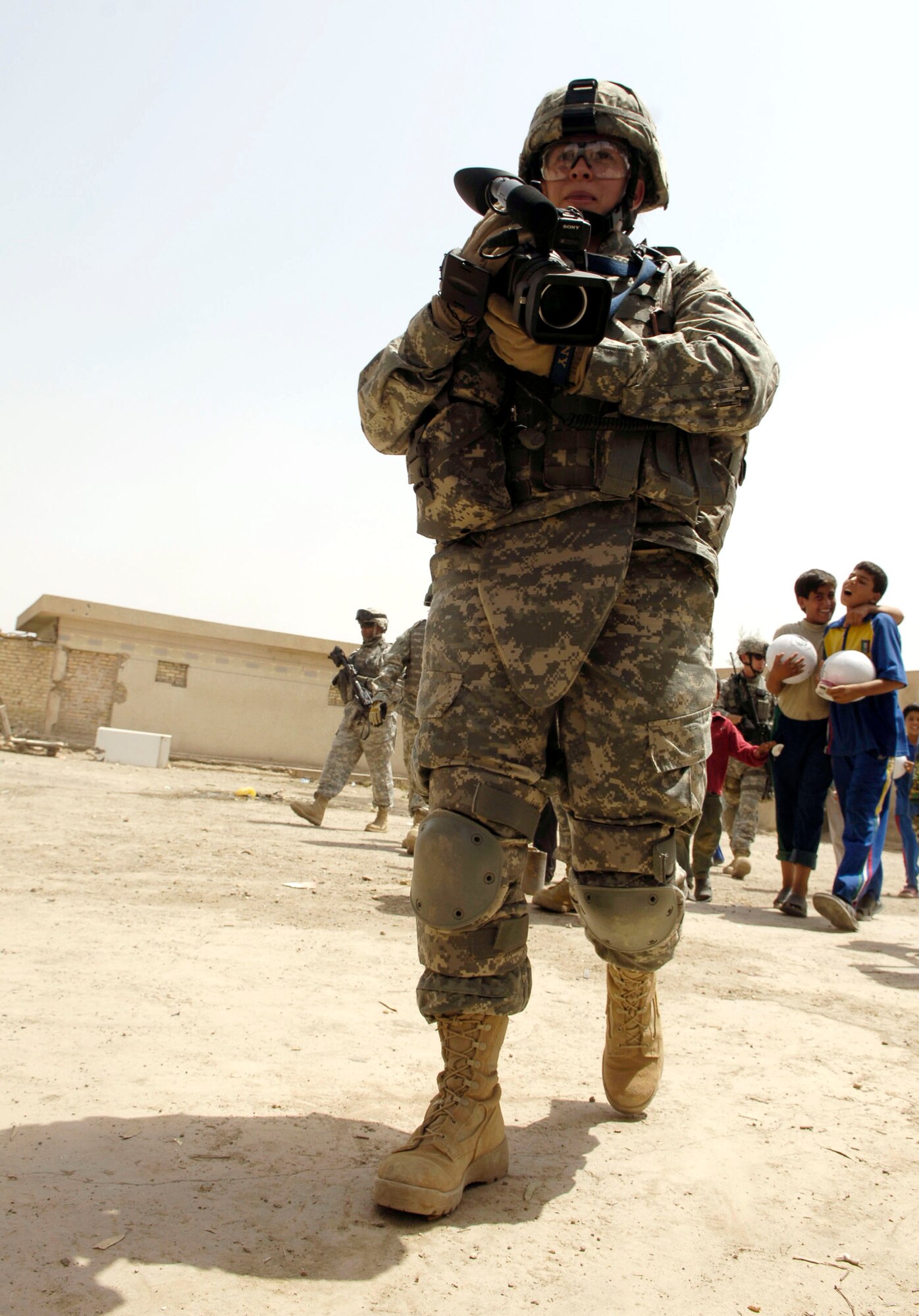 Senior Airman Geneva Stone captures happy moments May 24 of children getting gifts from the Iraqi National Police in Al Furat, Iraq. Airman Stone is a combat videographer assigned to the 1st Combat Camera Squadron in Charleston, S.C. During a recent humanitarian mission, U.S. servicemembers worked with the Iraqi police to distribute school supplies, toys and treats to Iraqi children. (U.S. Air Force photo/Master Sgt. Brian L. Boone)