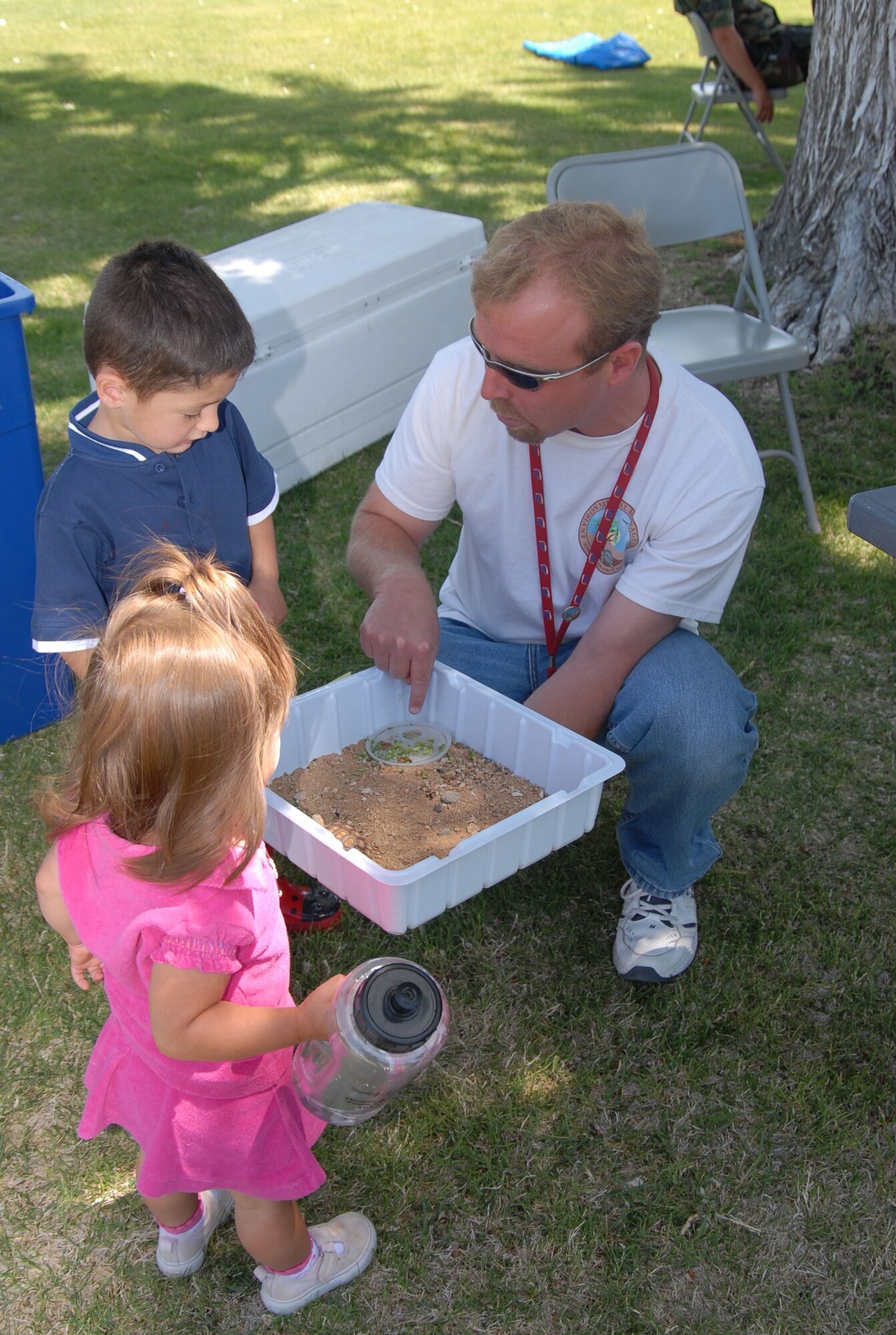 Wesley King (right), Environmental Management staff, shows a small desert tortoise to Zachary Clark (left), 3, and his sister Sophea (foreground), 1, during the 101 Critical Days of Summer Campaign Kickoff at the Oasis Community Center on May 24. (Photo by Airman 1st Class Julius Delos Reyes)