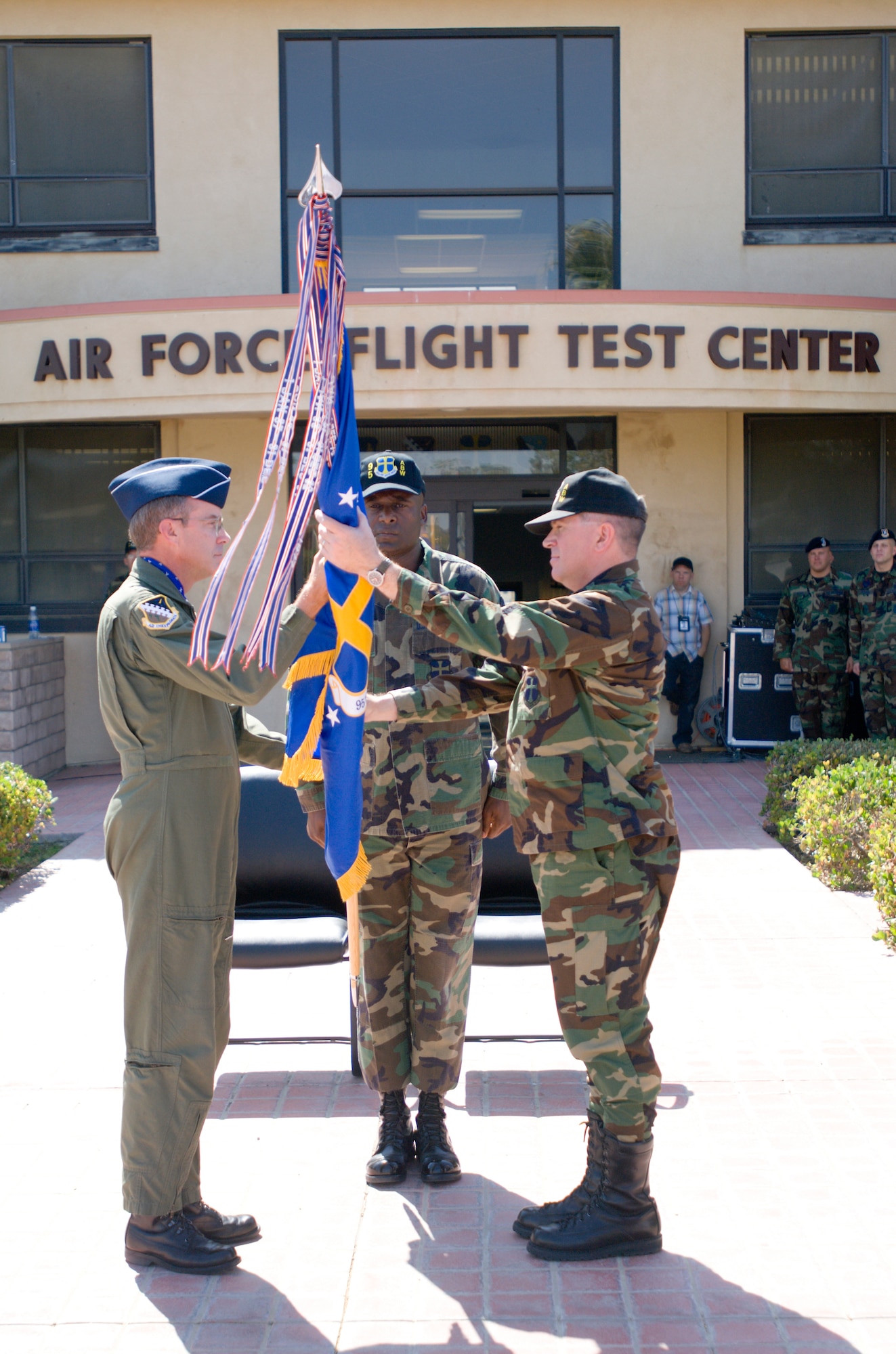 Maj. Gen. Curtis Bedke (left), Air Force Flight Test Center commander, hands over the 95th Air Base Wing flag to Col. Bryan Gallagher (right), former 95th ABW vice-commander, during an assumption of command ceremony at building 1 here May 29. With the ceremony, Colonel Gallagher officially took command of the 95th ABW. (Photo by Mike Cassidy)