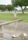 A Team Lackland firefighter responds to a severe weather military exercise May 21 at Lackland Air Force Base, Texas, by slinging a floatation device into a ditch in an effort to save two dummies depicting children swept away in heavy rain. Coincidentally, the exercise was interrupted by a real world severe weather situation which lasted much of the day. (USAF photo by Robbin Cresswell)