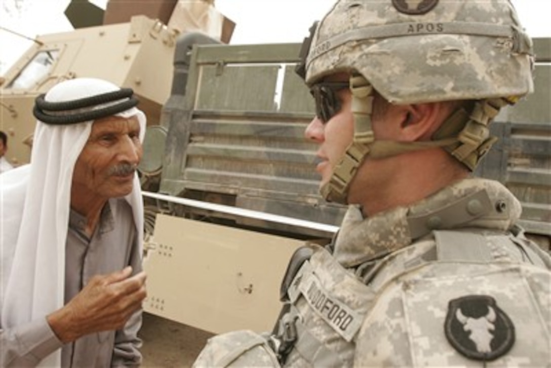 U.S. Army Sgt. Jeff Woodford speaks with an Iraqi man waiting to receive medical care during a cooperative medical engagement in Al Madinah As Siyahiyah, Iraq, on May 16, 2007.  Iraqi army soldiers from the 1st Iraqi Army Division, with assistance from U.S. Marines from Alpha Company, 2nd Combined Arms Battalion, 136th Infantry Regiment, 2nd Marine Logistics Group (Forward), are providing medical care to Iraqi civilians.   