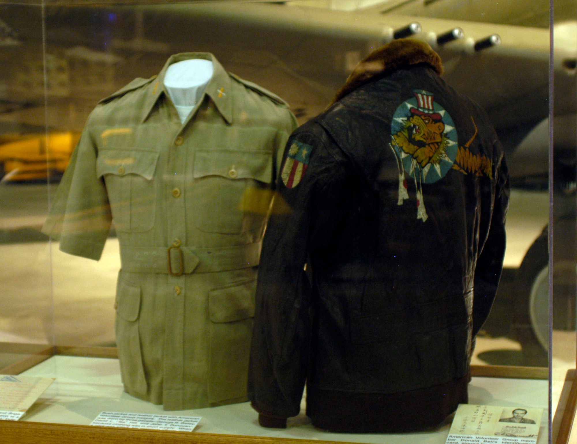 DAYTON, Ohio -- Bush jacket and leather leather jackets with American Volunteer Group insignia on display in the World War II Gallery at the National Museum of the U.S. Air Force. The leather jacket was worn by three people -- George R. Bailey, David L. "Tex" Hill and John T. Donovan -- because clothing was in short supply. When a pilot was killed, his personal effects were auctioned and the money sent home. The bush jacket was worn by Henry L. Olson. (U.S. Air Force photo)