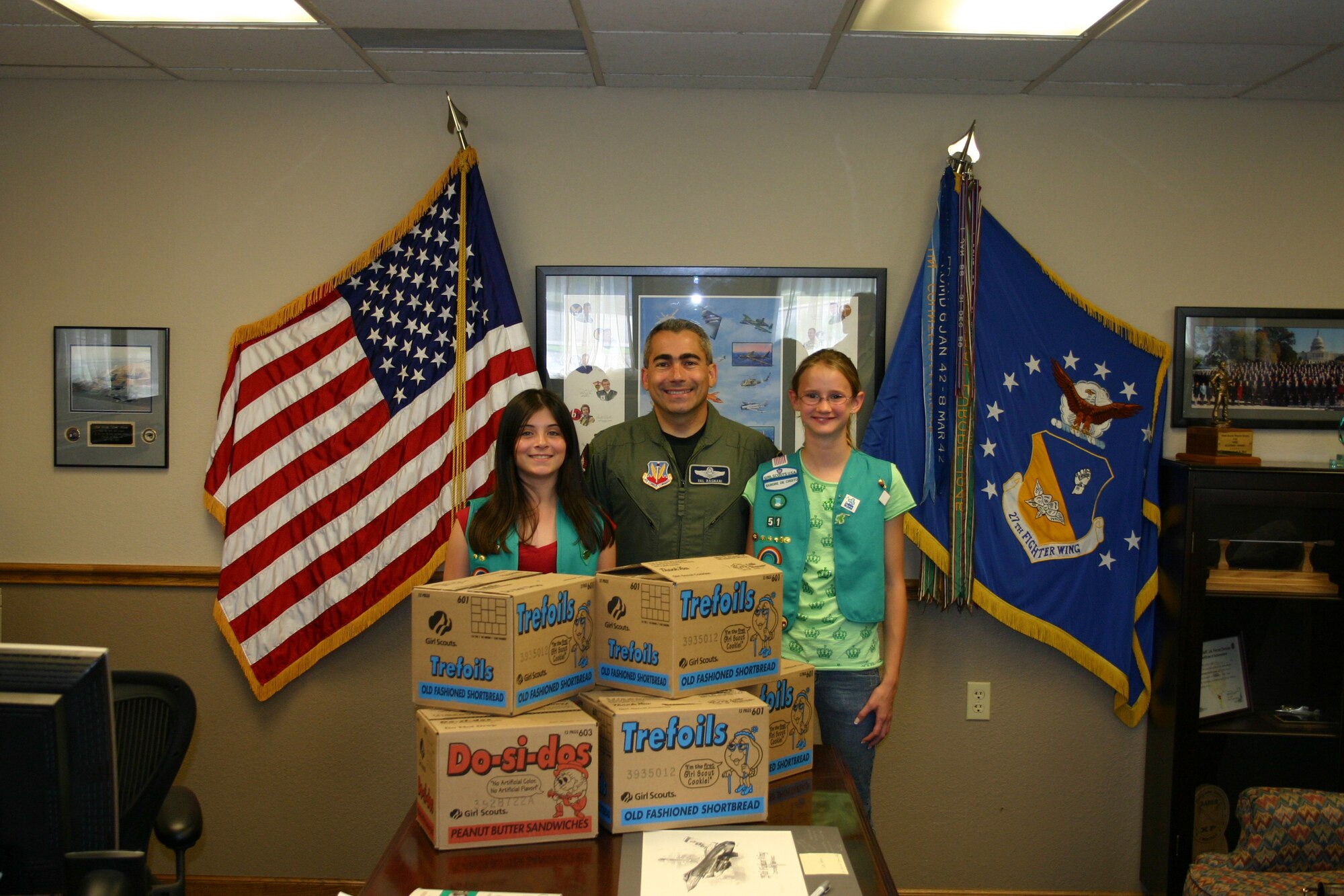 CANNON AIR FORCE BASE, N.M --Girl Scouts Angelina Garcia (left) and Rebecca Dewbre (right), from Girl Scout Troop 51, stand beside Colonel Valentino Bagnani III, 27th Fighter Wing vice commander, with boxes of Girl Scout cookies that will be sent to servicemembers serving in Afghanistan and Iraq. (U.S. Air Force photo by Airman Elliott Sprehe)
