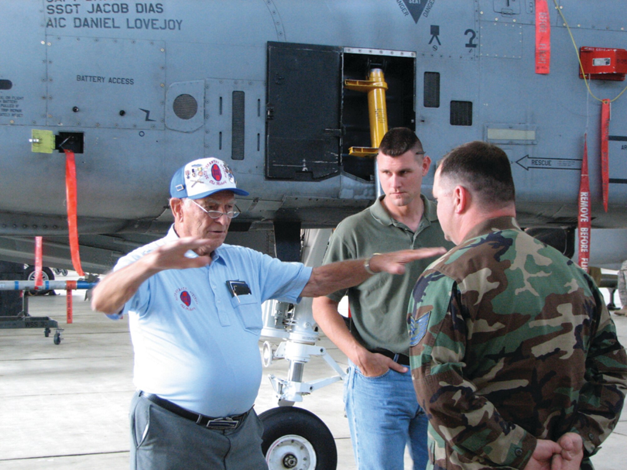 SPANGDAHLEM AIR BASE, GERMANY -- World War II veteran 1st Lt. Frank Towers and grandson Duane King, an active-duty U.S. Marine Corps Staff Sergeant stationed in Louisiana, discuss the A-10’s weapons systems and differences between World War II’s Air Force and today’s Air Force with Tech. Sgt. Justin Fair, 52nd Maintenance Operations Squadron weapons loading standardization crew member, May 24. Mr. Towers and his grandson, who is a member of the Marine Corps Band, toured the hangar where Sergeant Fair works as part of their visit to Spangdahlem Air Base. (US Air Force photo/Master Sgt. George King)
