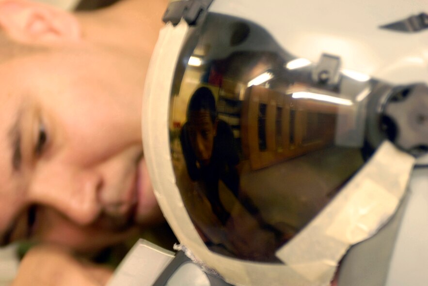 KUNSAN AIR BASE, South Korea -- Staff Sgt. William Correa, background, and Senior Airman Cortney Tanner make adjustments to Capt. Darin Wetzler’s custom visor for his new Joint Helmet Mounted Cueing System Nov. 1 here. Both SSgt. Correa and SrA Tanner are aircrew flight equipment journeyman with the 8th Operation Support Squadron. Airman received hands-on trainingfrom a Boeing instructor on how to size, fit, inspect and maintain the JHMCS helmet and related sub-systems. (U.S. Air Force photo/Senior Airman Steven R. Doty)