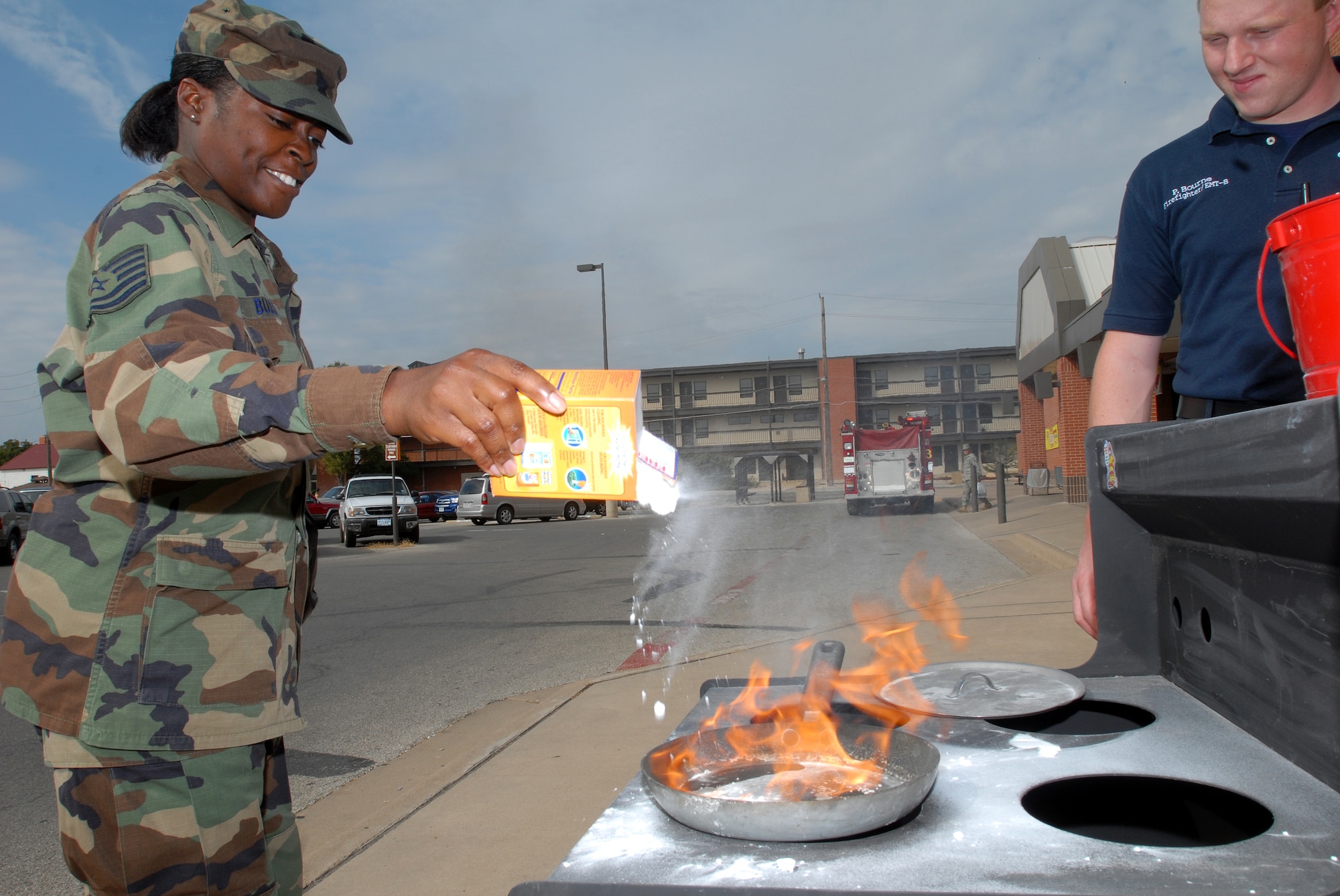 Tech. Sgt. Taniesha Bussey, an instructor with the 316th Training Squadron, puts out a fire as Paul Bourne, a firefighter with the Goodfellow Air Force Base Fire Department, monitors her progress during the Grease Fire Demonstration Oct. 10 at the Base Exchange. (U.S. Air Force photo by Tech. Sgt. Gina O’Bryan)