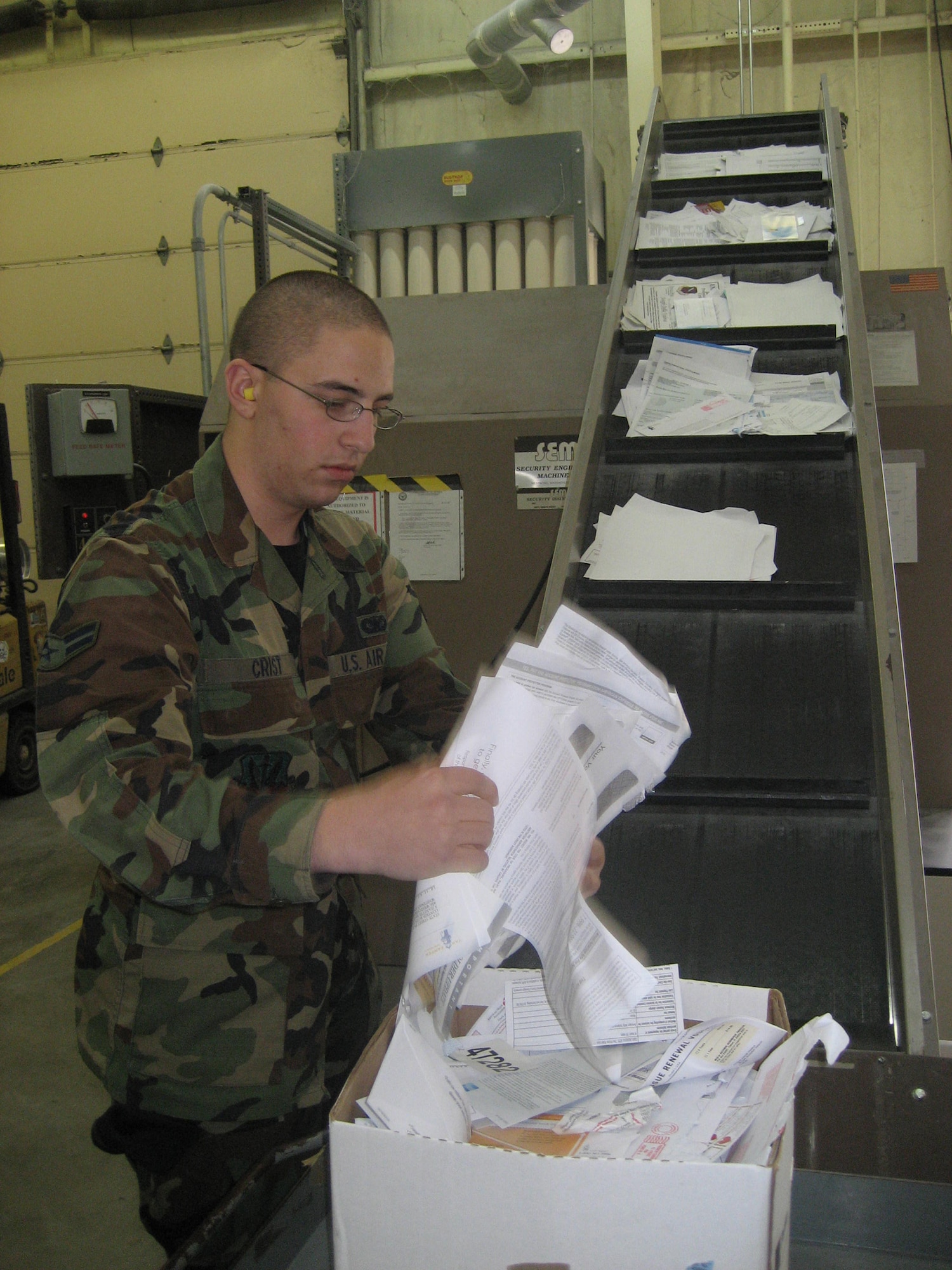 WHITEMAN AIR FORCE BASE, Mo. -- Airman 1st Class Jonathon Crist, 509th Security Forces Squadron, assists with destroying documents in a disintegrator Oct 26. As waste is fed into the unit, it falls down a chute into a destruction chamber which contains a rotor with five knives mounted to it. The five rotating knives pass by two stationary bed knives and cut the waste smaller and smaller with each pass. The size of the final waste is determined by an interchangeable security screen. Once the waste is small enough to pass through the screen it drops out of the destruction chamber and is moved into a waste collection bin. (U.S. Air Force photo/Maj. Joe DellaVedova)