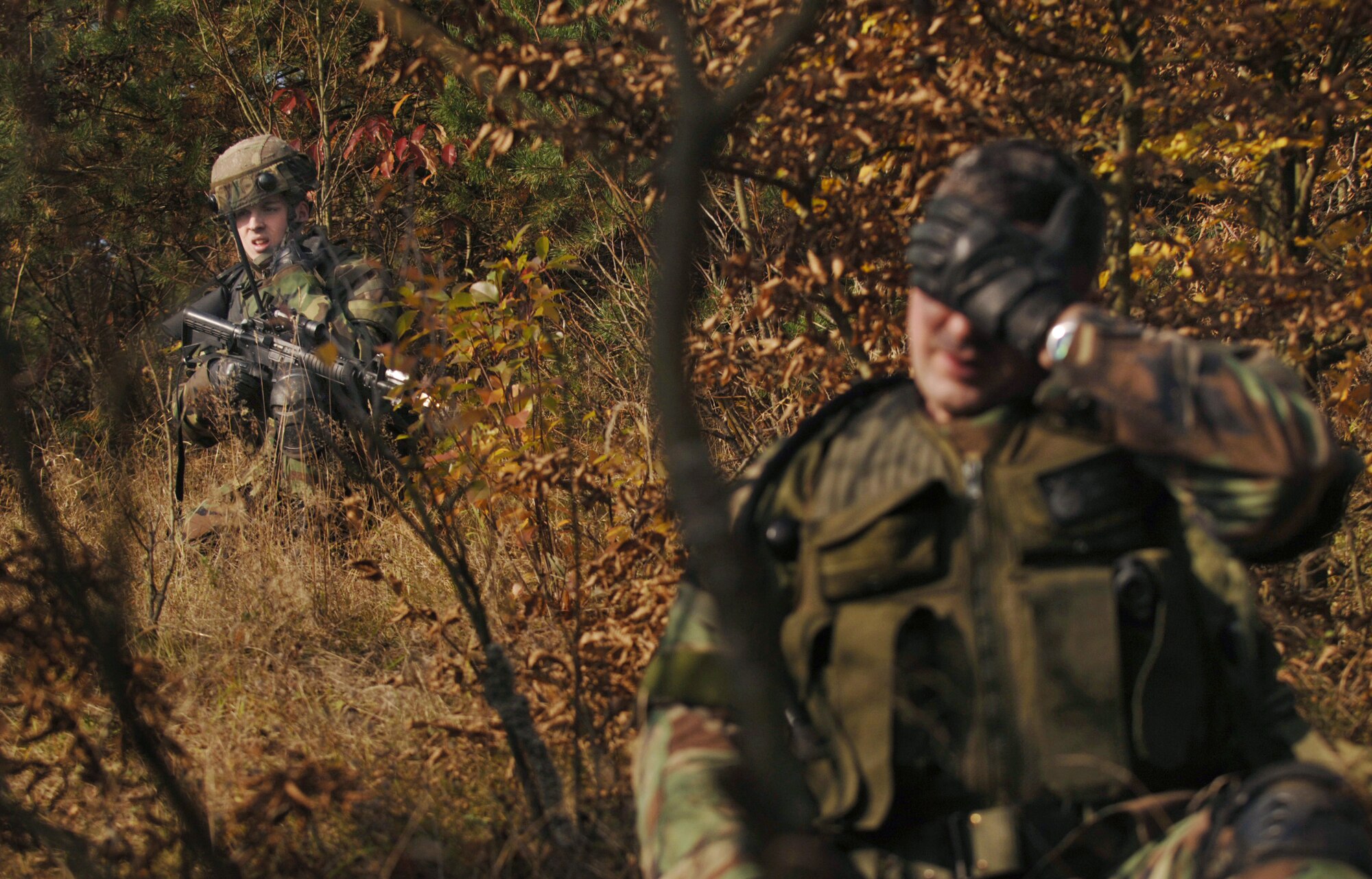 As the sole survivor of a simulated fire fight, Airman 1st Class Stephan Argyro (left) waits for Creek Defender instructors to evaluate the convoy patrol scenario that "killed" fellow security forces member Staff Sgt. James Horan Oct. 23 on Baumholder U.S. Army Garrison, Germany.  The Airmen and 104 other U.S. Air Forces Europe police were training at the two-week pre-deployment integrated base defense course taught by the 786th Security Forces Squadron's regional training center. Both Airmen are assigned to the 100th Security Forces Squadron at Royal Air Force Mildenhall, England. (U.S. Air Force photo/Master Sgt. Scott Wagers)