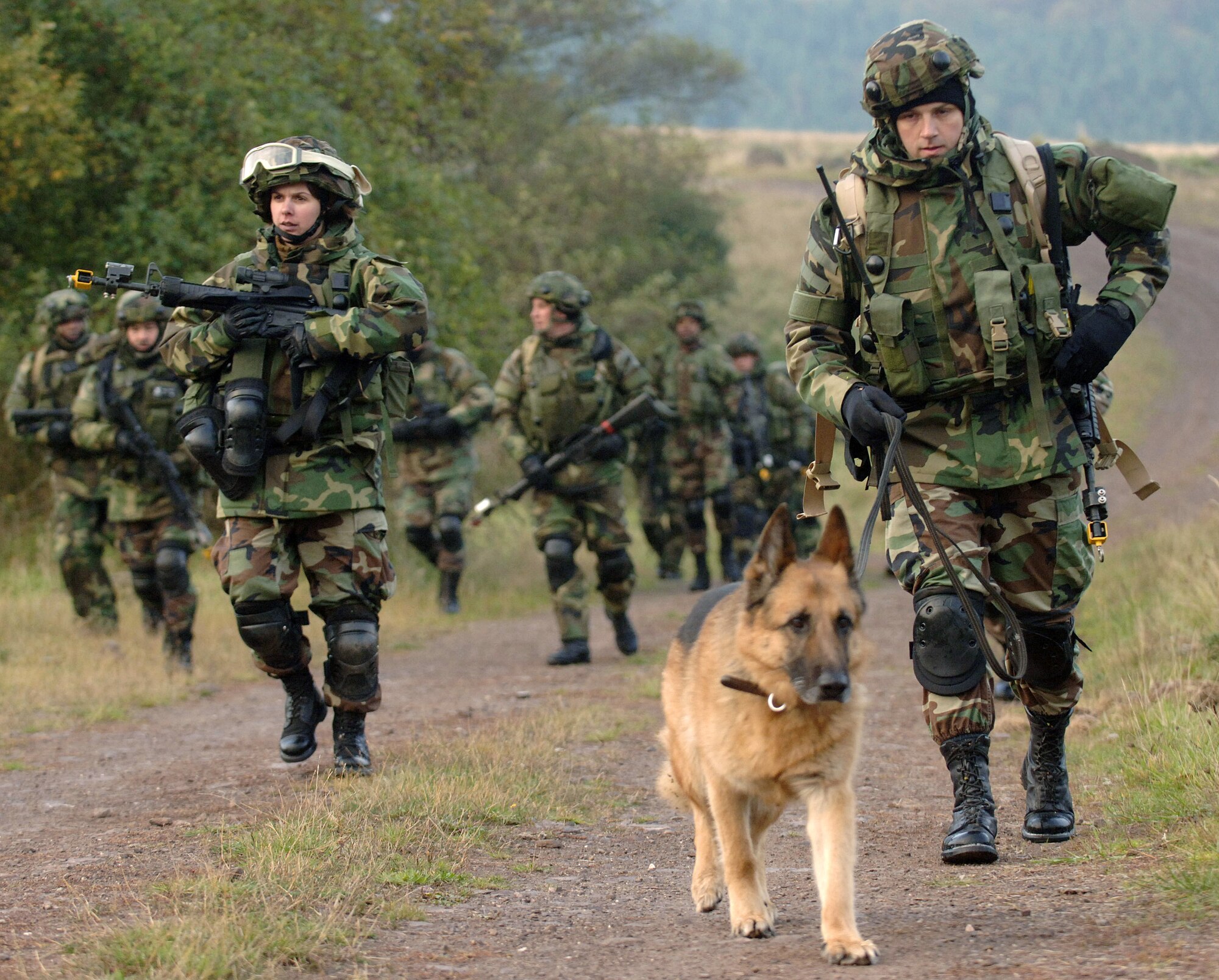Staff Sergeant Mark Reidl and his "partner" Lord, an 8-yr-old German Shepherd, lead a foot patrol Oct. 23 with 1st Lt. Kristen Congelosi and other security forces Airmen taking part in a two-week re-deployment integrated base defense course known as Creek Defender at Baumholder U.S. Army Garrison in southern Germany.  Sergeant Reidl is a K-9 handler with the 435th Security Forces Squadron at Ramstein Air Base, Germany, and Lieutenant Cogelosi is with the 100th Security Forces Squadron at Royal Air Force Mildenhall, England.  (U.S. Air Force photo/Master Sgt. Scott Wagers)