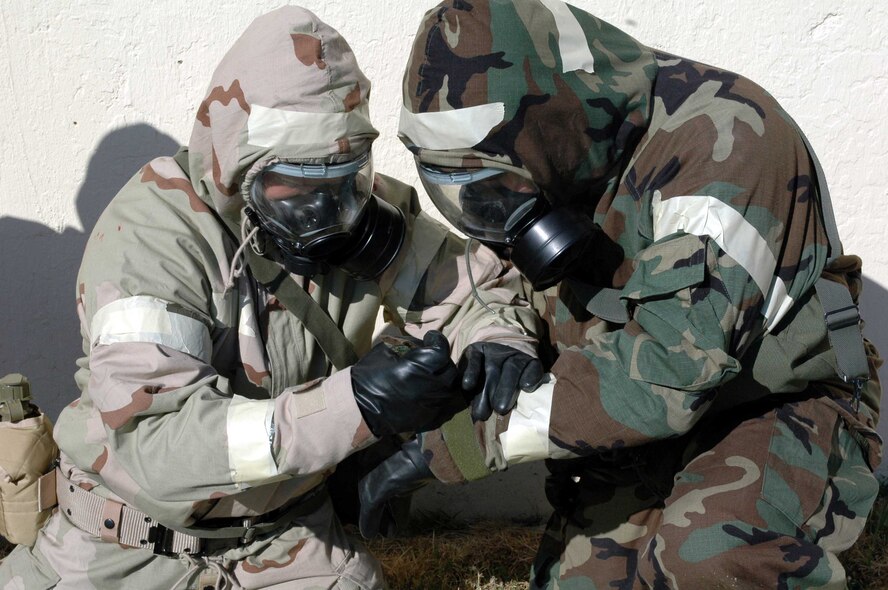 A Chemical, Biological, Radiological, Nuclear, Explosives Defense Survival Skills training course student ensures his wingman's chemical warfare gear is properly secured. Course instructors recently instituted new and improved changes to the class format emphasizing the importance of wearing chemical warfare gear properly. (U.S. Air Force photo/Staff Sgt. Candy Knight)