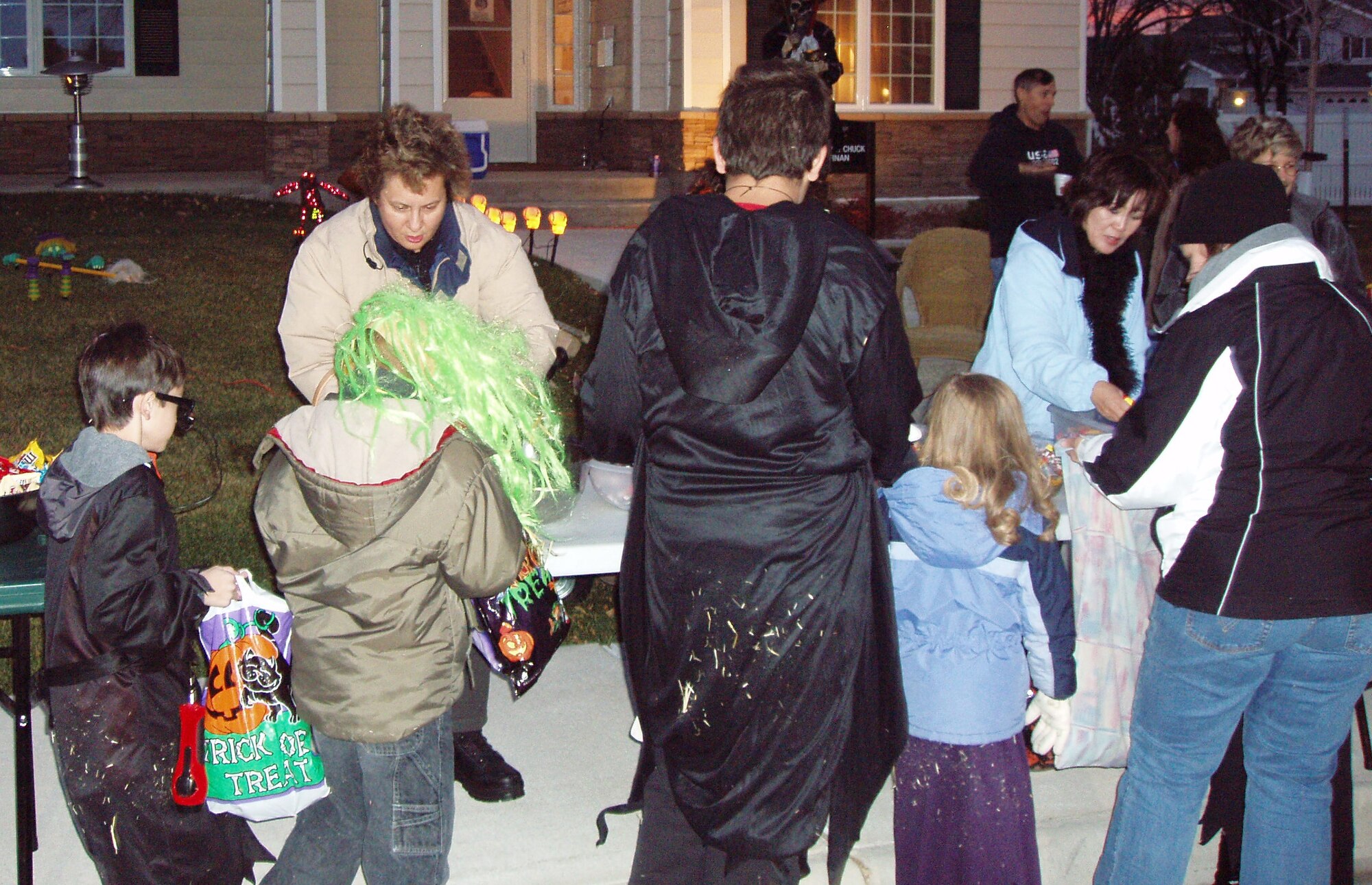 Col. Sandy Finan, 341st Space Wing commander, left, and Malinda Asher, right, hand out Halloween treats in front of the commander's quarters Oct. 31. (Courtesy photo)      
