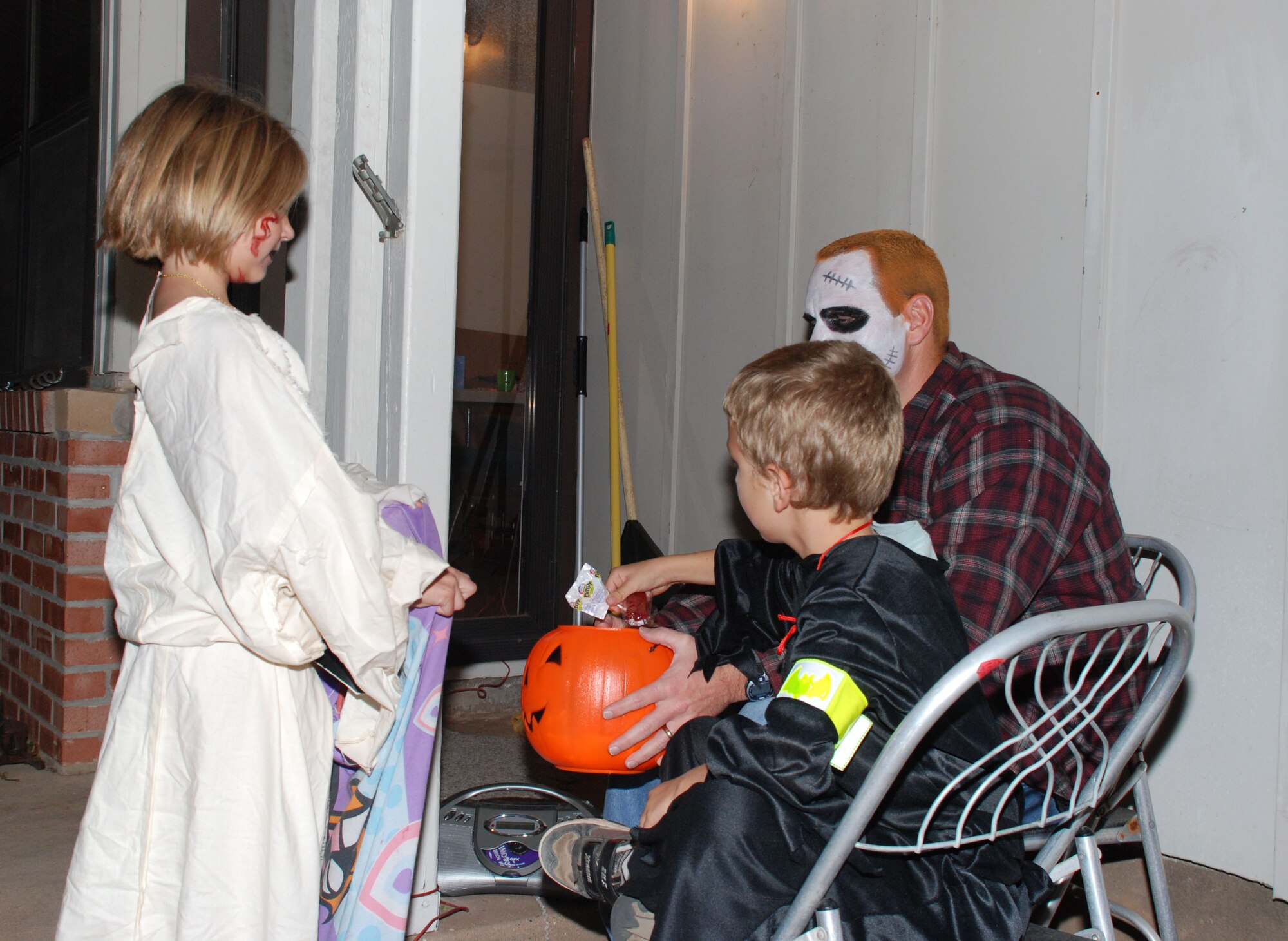 Navy Petty Officer 1st Class Dennis Dudley, a personnel specialist with the 366th Training Squadron and his son Zachary, hand out candy to Jennifer Sheets, daughter of Kristen Sheets Oct 31 in Wherry Housing. (U.S. Air Force photo/Airman 1st Class Jacob Corbin