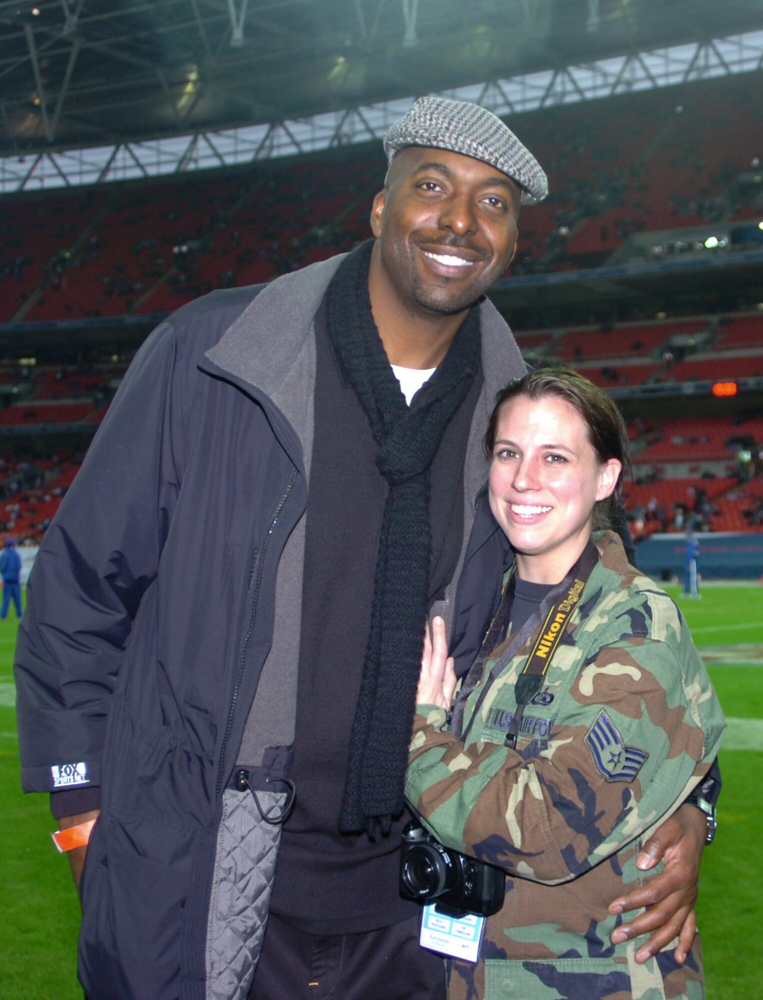 It's All Relative!  Air Force Staff Sgt. Jocelyn L. Rich stands a good 5 feet 7 inches, but is dwarfed by 6 Foot. 11 inch broadcaster and former basketball star John Salley.  Staff Sgt Rich, a military photographer was covering the JAC honor guard's performance at the first ever regular season NFL game played in London, England.  Mr. Salley was broadcasting from the game for "The Best Darn Sports Show." (USAF Photo)