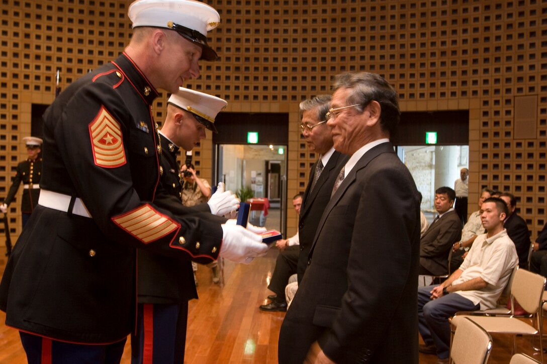 IE SHIMA, OKINAWA, Japan ? Sgt. Maj. Robert E. Mastriano, the sergeant major of Marine Corps Bases Japan, and 1st Lt. Ralph Lemaster, the officer in charge of the Ie Shima Training Facility, present the Mayor of Ie Shima, Katsumasa Oshiro, and Ie Shima?s Speaker of the House, Hiroaki Uchima, Marine Corps birthday coins on Ie Shima Nov. 2.