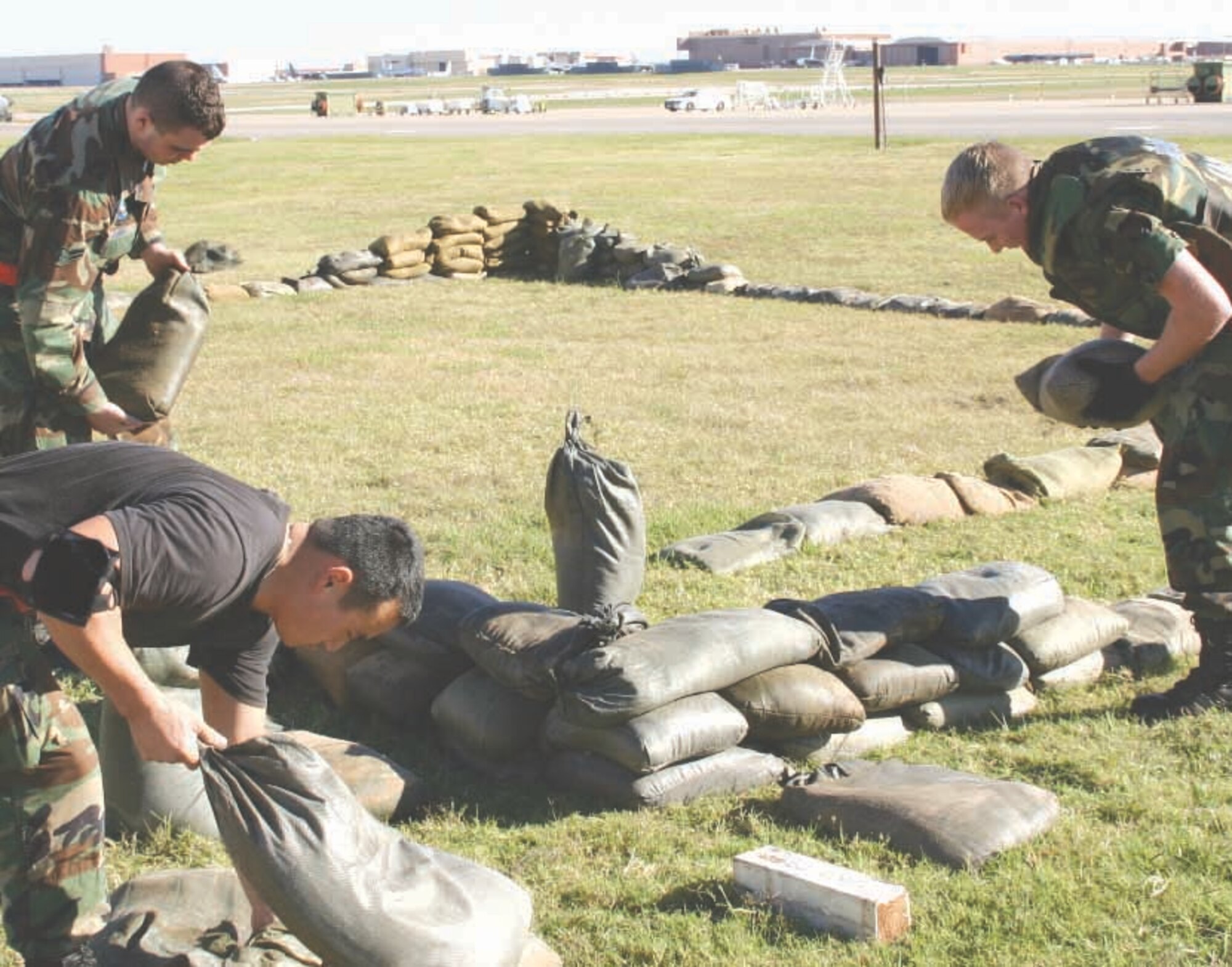 Airmen from the 552nd Maintenance Group fill and stack sandbags at South Ramp to make an outdoor bunker for red and black alarm conditions. (Air Force photo by Senior Airman Lorraine Amaro)