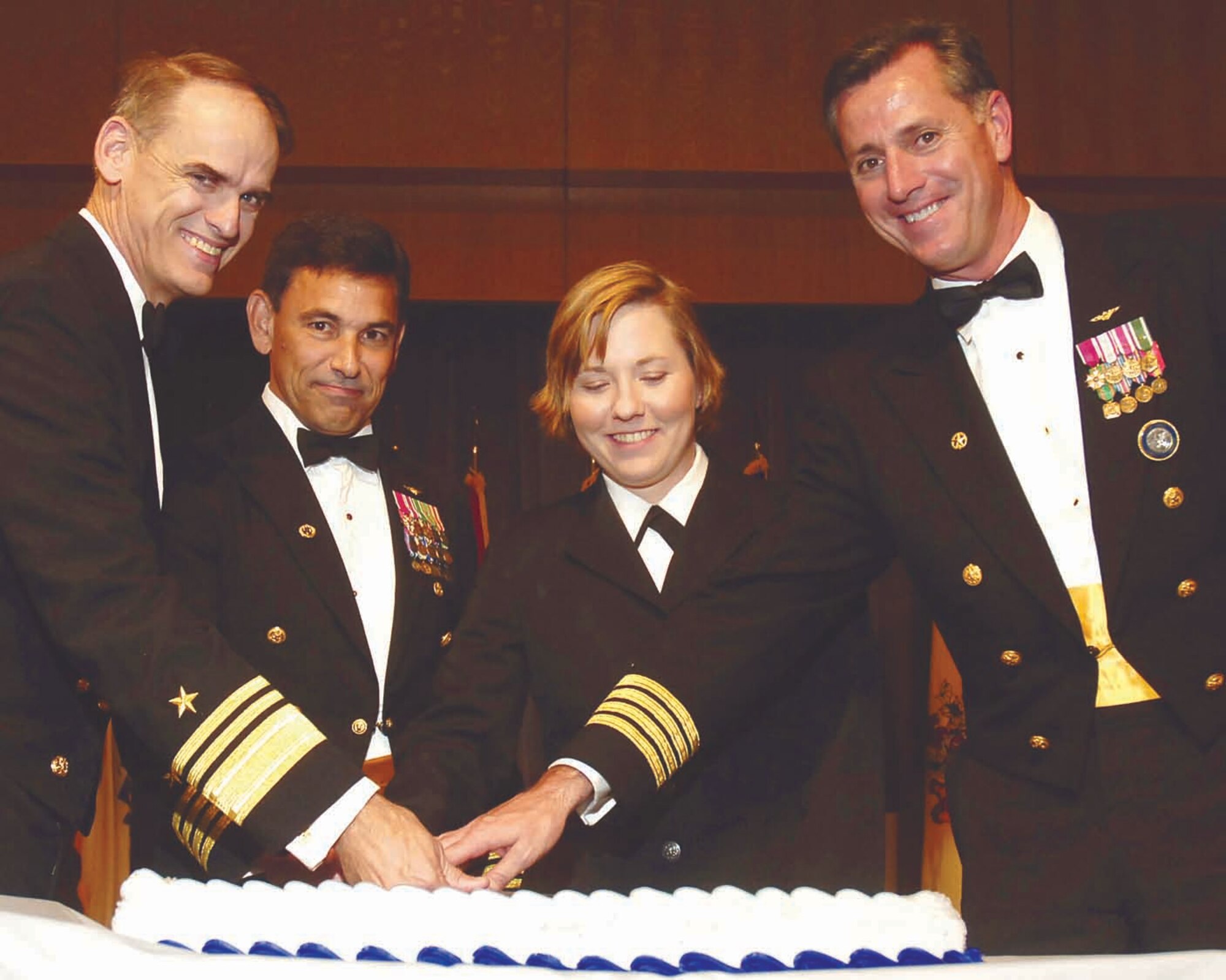 Rear Adm. Thomas J. Kilcline, left, and Capt. Brian Costello, right, cut the Navy’s 232nd Birthday cake with assistance from the most senior and junior Sailors in attendance. (Air Force photo by Dave Faytinger)