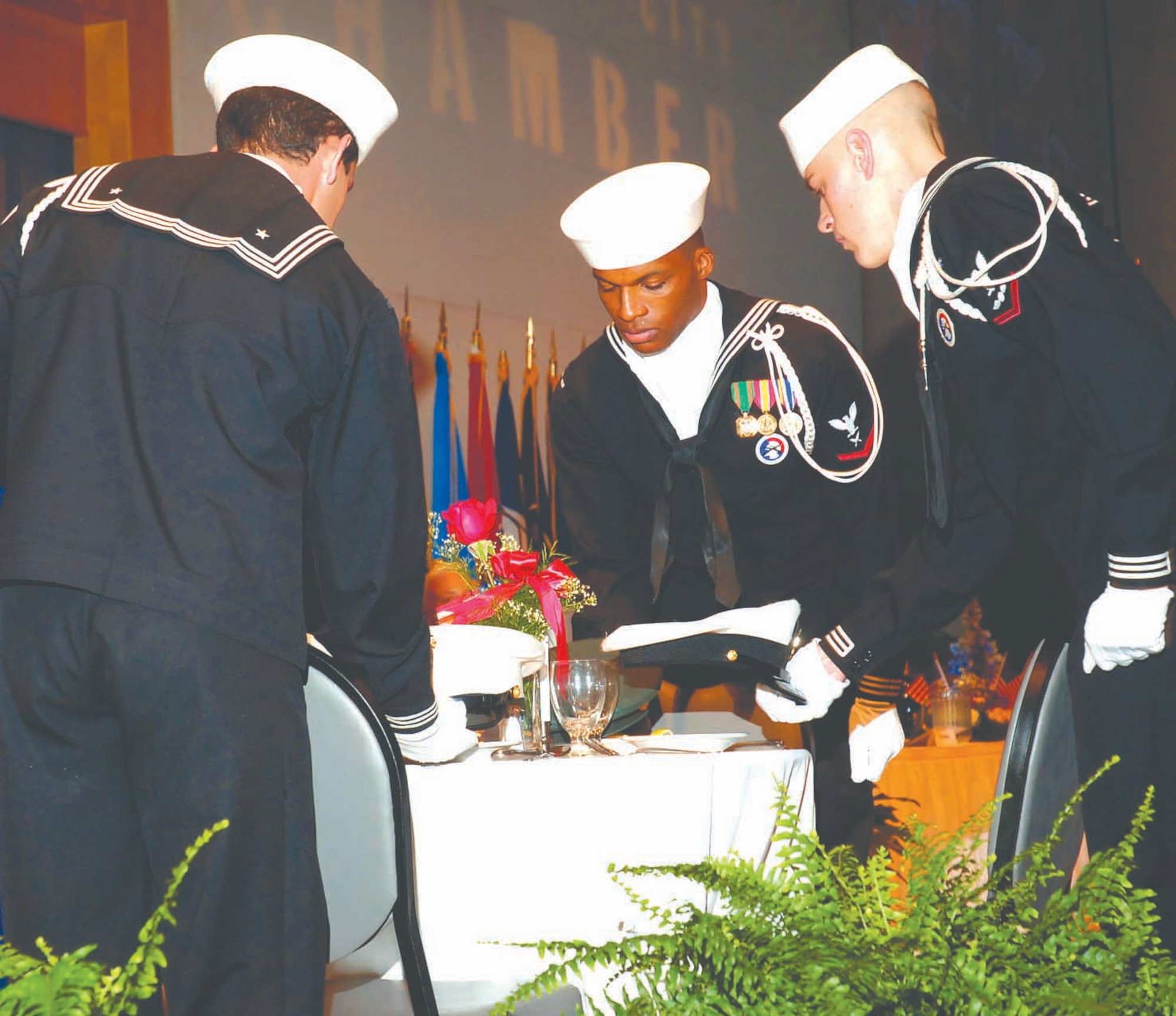 Airman Joan Beauchamp, Petty Officer 3rd Class Jermaine Gilmore and Airman Martin place Navy covers on a dinner table representing servicemembers who have sacrificed their lives in defense of the country. This is a yearly ceremony at the Birthday Ball. (Air Force photo by Dave Faytinger)