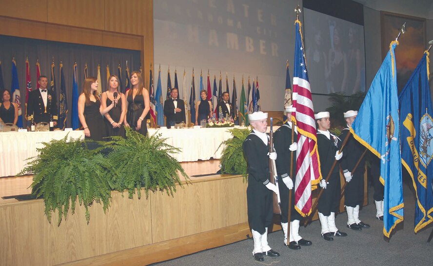 Clare, Katy and Carly Costello sing the National Anthem at the 16th Oklahoma Navy Birthday Ball as the TACAMO Honor Guard posts the colors. The Oklahoma Ball is the largest in the continental United States, with more than 1,000 people in attendance. (Air Force photo by Dave Faytinger)