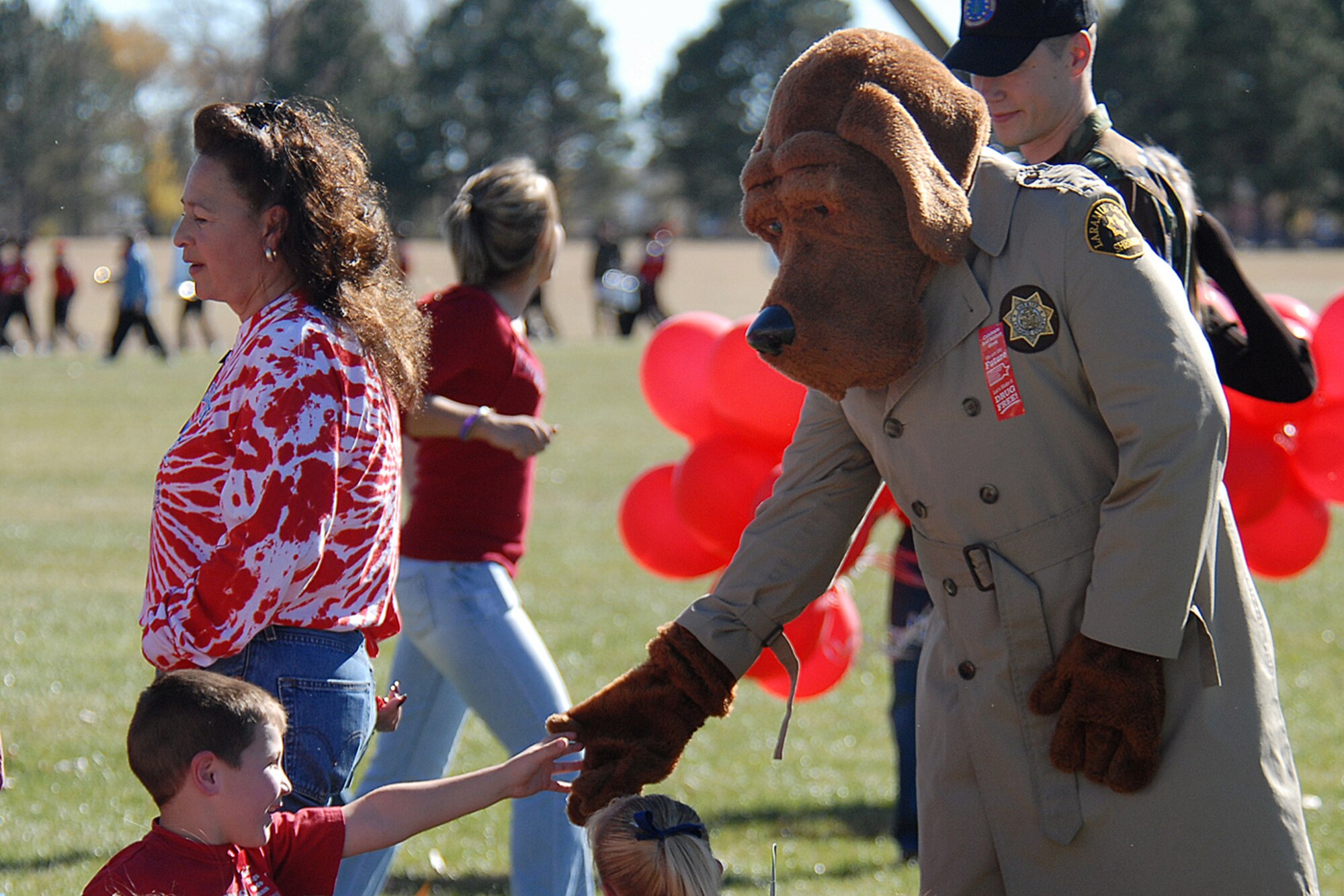 Chase Chadick, a 1st grader at Freedom Elementary School, shakes McGruff the Crime Dog’s hand, played by Senior Airman Armando Geneyro, 90th Mission Operations Squadron, during the Red Ribbon Week parade here. McGruff the Crime Dog is a nationwide icon for crime prevention.