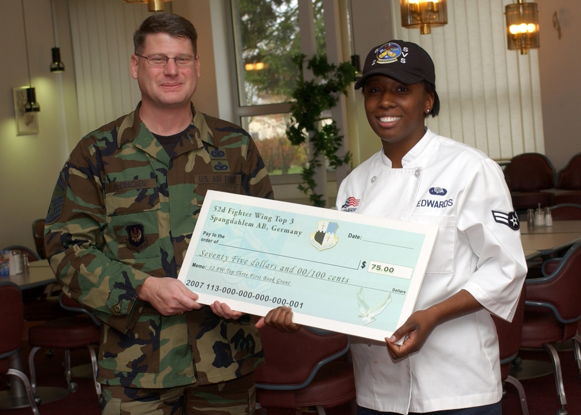 SPANGDAHLEM AIR BASE, Germany -- Senior Master Sgt. Patrick McCracken, 52nd Fighter Wing Top 3 Education Committee, presents Airman 1st Class Patrice Edwards, 52nd Services Squadron, with a First Book Grant of $75. The First Book program was initiated to encourage Airmen to continue their education. (U.S. Air Force photo/Airman 1st Class Allen Pollard)   