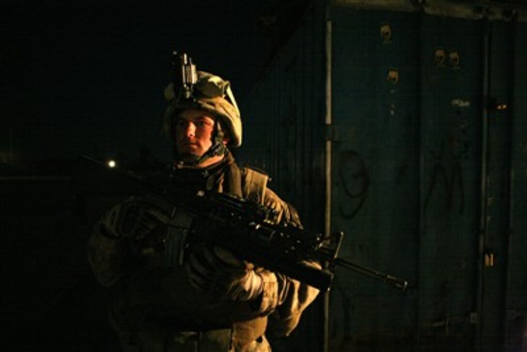A U.S. Marine with 3rd Battalion, 5th Marine Regiment, Regimental Combat Team 6 stops in front of a large storage container during a security halt on a night patrol in the Sina'a industrial district of Fallujah, Iraq, on Oct. 23, 2007.  