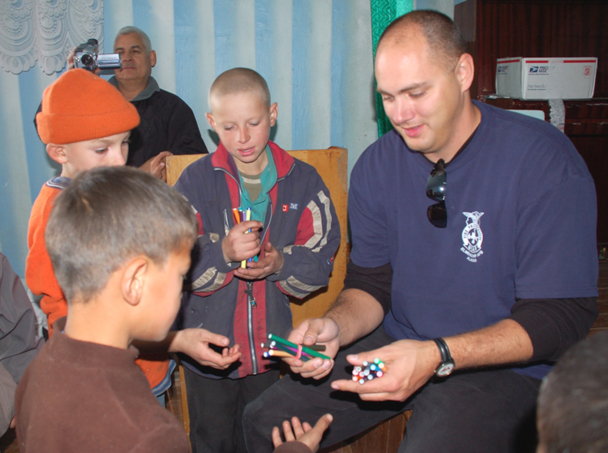 Master Sgt. Joseph Debets, 376th Expeditionary Civil Engineer Squadron, passes out colored markers to children at the Tok Mok II Orphanage. (Air Force photo by Senior Master Sgt. Stefan Alford).