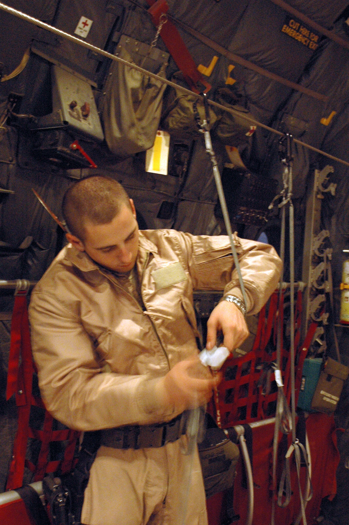 SOUTHWEST ASIA - Senior Airman William Moody, 40th Expeditionary Airlift Squadron loadmaster, sets up static lines to help rip open boxes of leaflets. (U.S. Air Force photo/Staff Sgt. Jason Barebo)