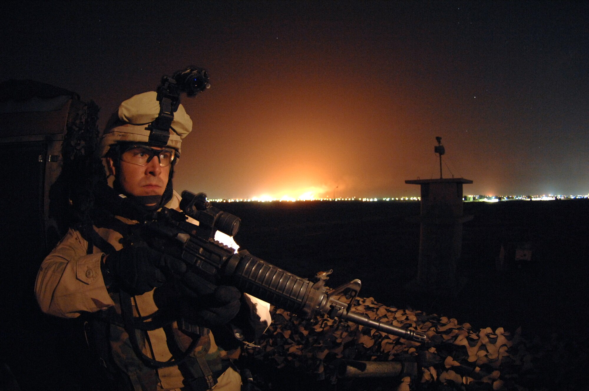 KIRKUK REGIONAL AIR BASE, Iraq - Senior Airman Thomas Benincosa, 506th Expeditionary Security Forces Squadron, keeps a vigilant eye during night operations here Nov. 2. In the background, oil refineries burn off excess oil. Airman Benincosa works mid-shift for Alpha flight doing patrols around the perimeter of the base and on guard stations along the fence line.  Kirkuk is the only base in Iraq completely patrolled and guarded by Air Force Security Forces and Airman Benincosa is just one of many security forces members making that happen.  Airman Benincosa is deployed from the 419th Security Forces Squadron at Hill Air Force Base, Utah.
(U.S. Air Force Photo/Senior Airman Jeremy McGuffin)