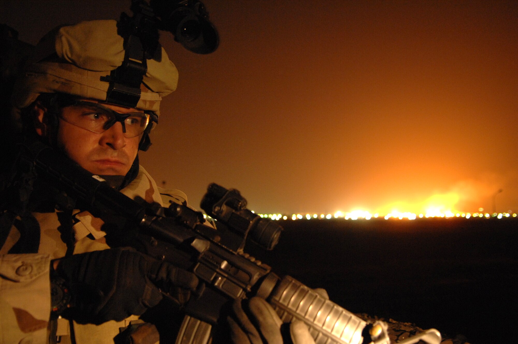 KIRKUK REGIONAL AIR BASE, Iraq - Senior Airman Thomas Benincosa, 506th Expeditionary Security Forces Squadron, keeps a vigilant eye during night operations here Nov. 2. In the background, oil refineries burn off excess oil. Airman Benincosa works mid-shift for Alpha flight doing patrols around the perimeter of the base and on guard stations along the fence line.  Kirkuk is the only base in Iraq completely patrolled and guarded by Air Force Security Forces and Airman Benincosa is just one of many security forces members making that happen.  Airman Benincosa is deployed from the 419th Security Forces Squadron at Hill Air Force Base, Utah.
(U.S. Air Force Photo/Senior Airman Jeremy McGuffin)
