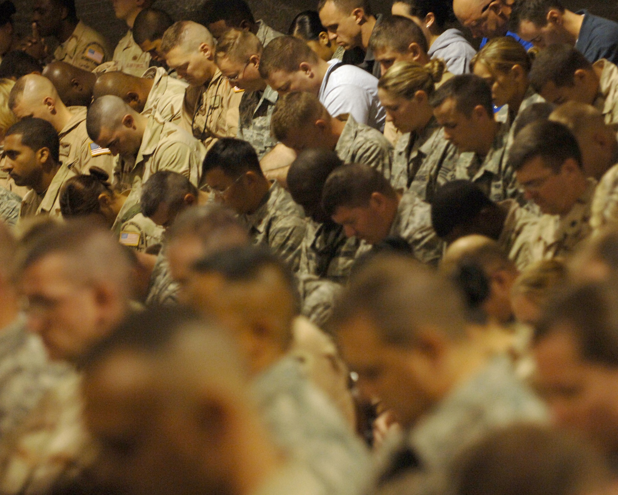 BALAD AIR BASE, Iraq -- More than 300 Airmen and Soldiers bow their heads in prayer during a memorial service here, Nov. 4, to honor the service and sacrifice of three fallen Airmen. Special Agents Thomas Crowell, David Wieger and Nathan Schuldheiss of Air Force Office of Special Investigations Expeditionary Detachment 2411 died Nov. 1, of wounds sustained from an improvised explosive device. Brig. Gen. Dana Simmons, AFOSI commander, spoke during the memorial, challenging those present "to continue the fight and honor these heroes' sacrifice." (U.S. Air Force photo/Maj. John Sheets)