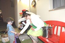 Stephanie Rickert, Marine Air Control Group 18, passes out candy to a child Halloween night. (U.S. Air Force photo/Airman 1st Class Kasey Zickmund)
